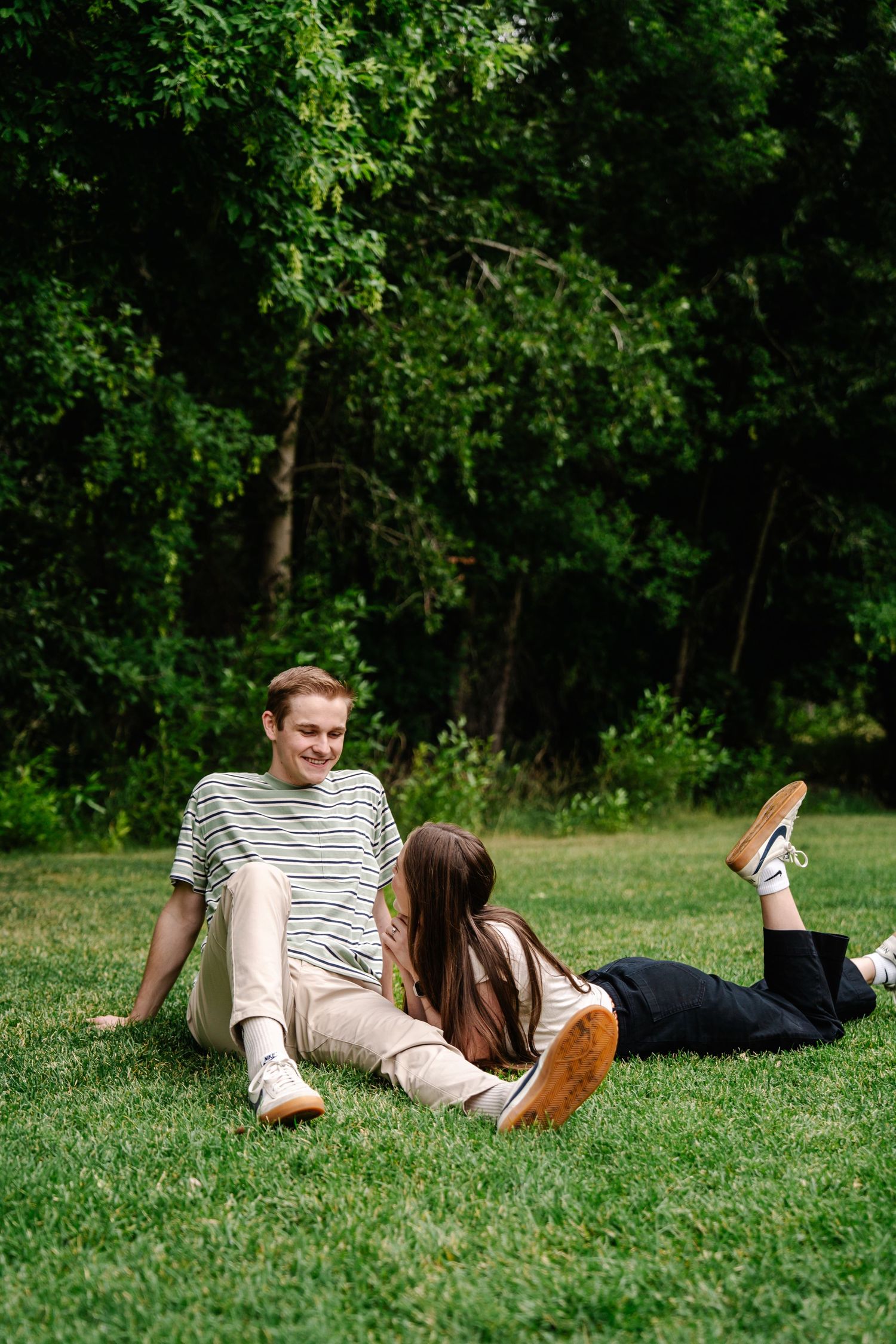 Couple relaxing together on lush green grass in a park setting.