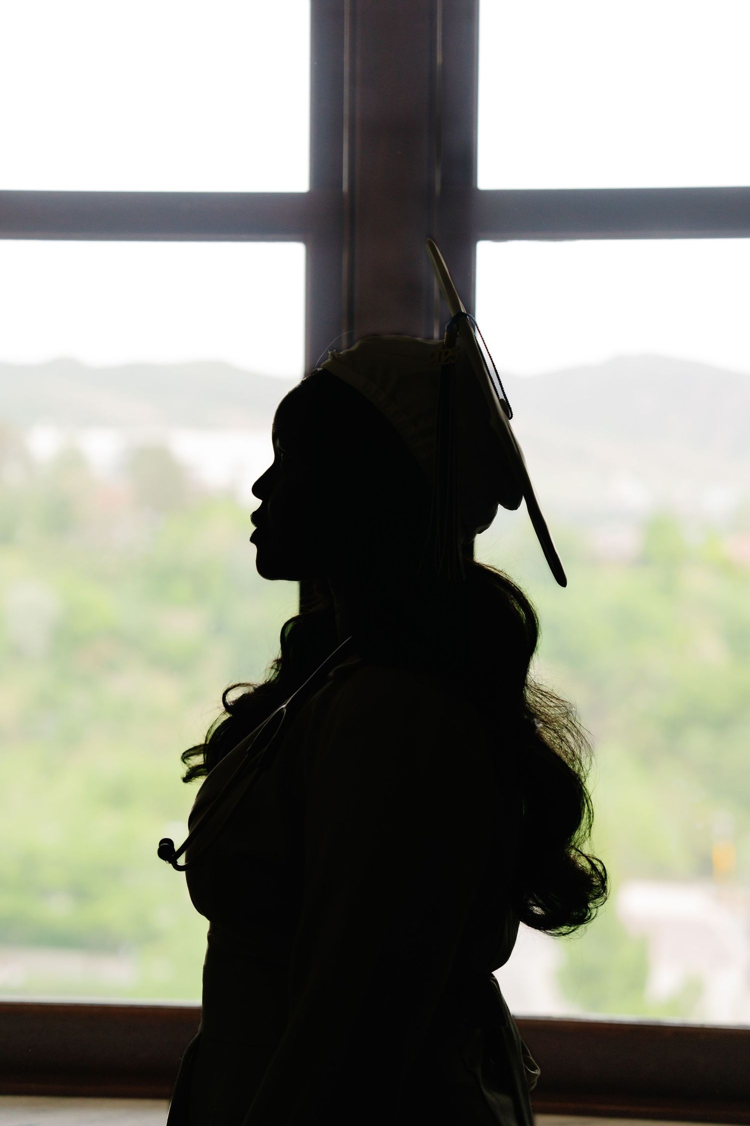Silhouette profiles against a bright window with a scenic outdoor view.