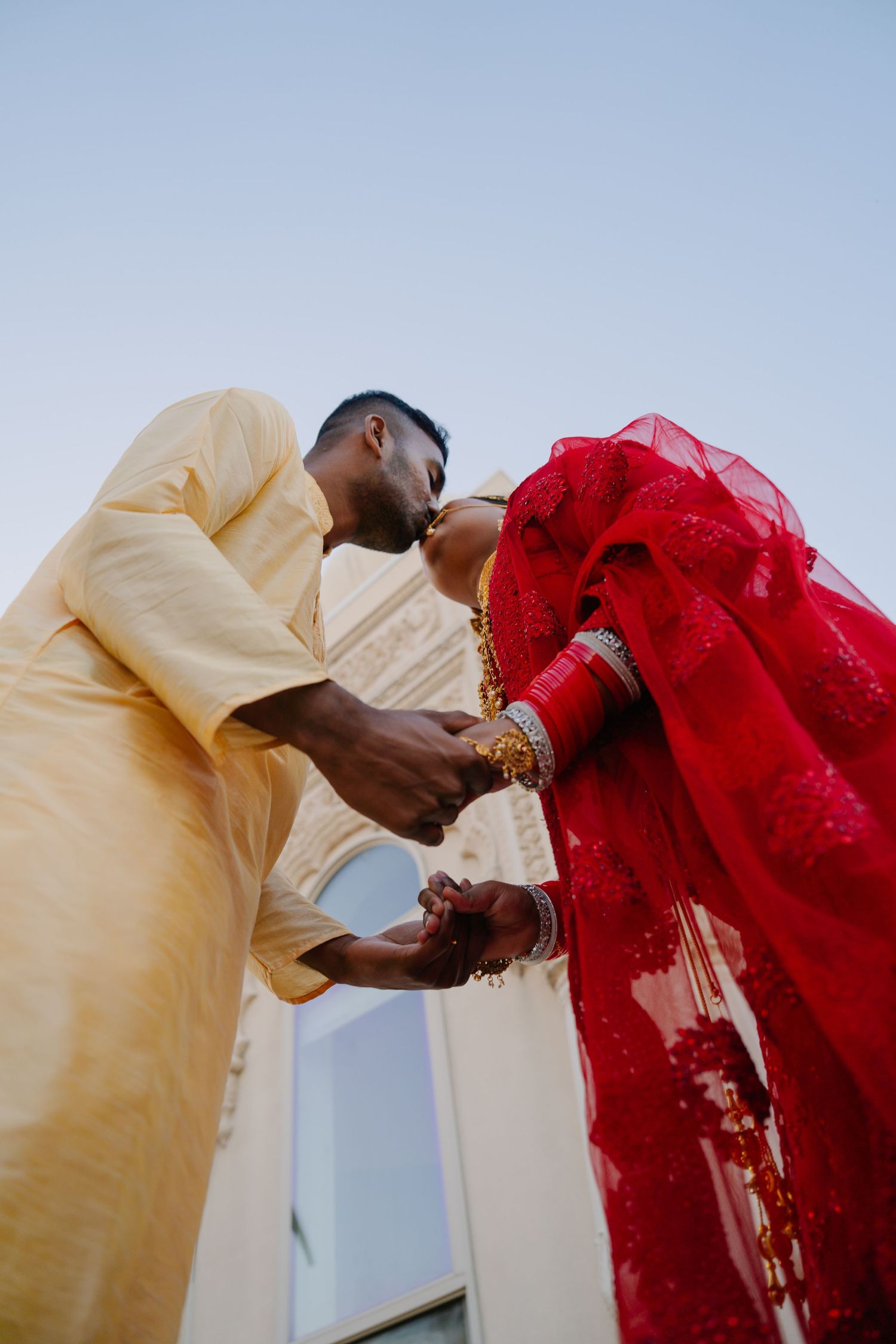 A romantic moment captured between a couple in traditional yellow and red wedding attire.