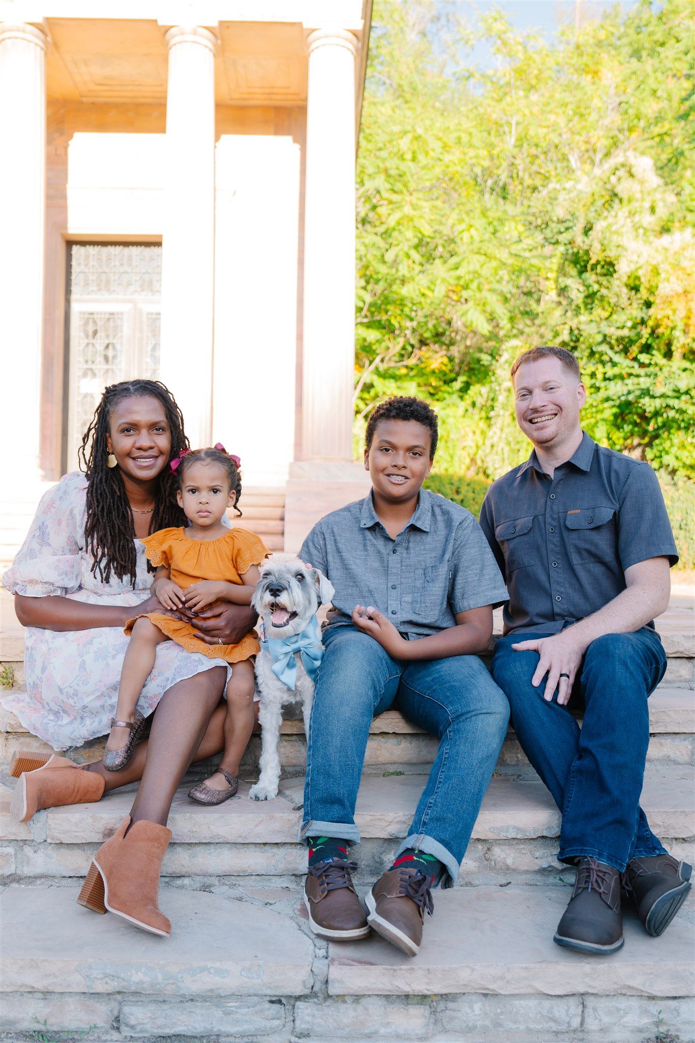 Group portrait of people sitting casually on concrete steps outdoors.
