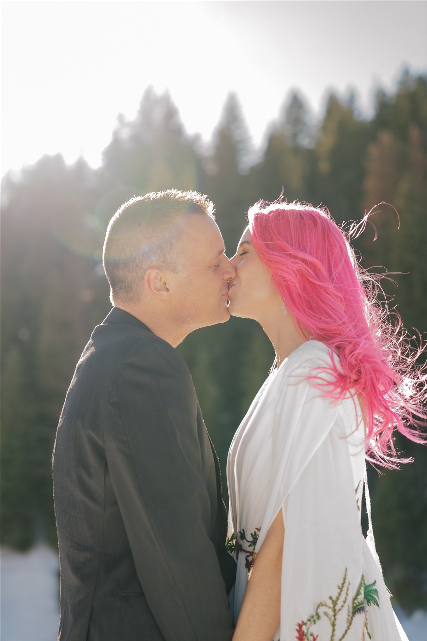 Silhouetted couple sharing an intimate moment against a bright winter landscape.