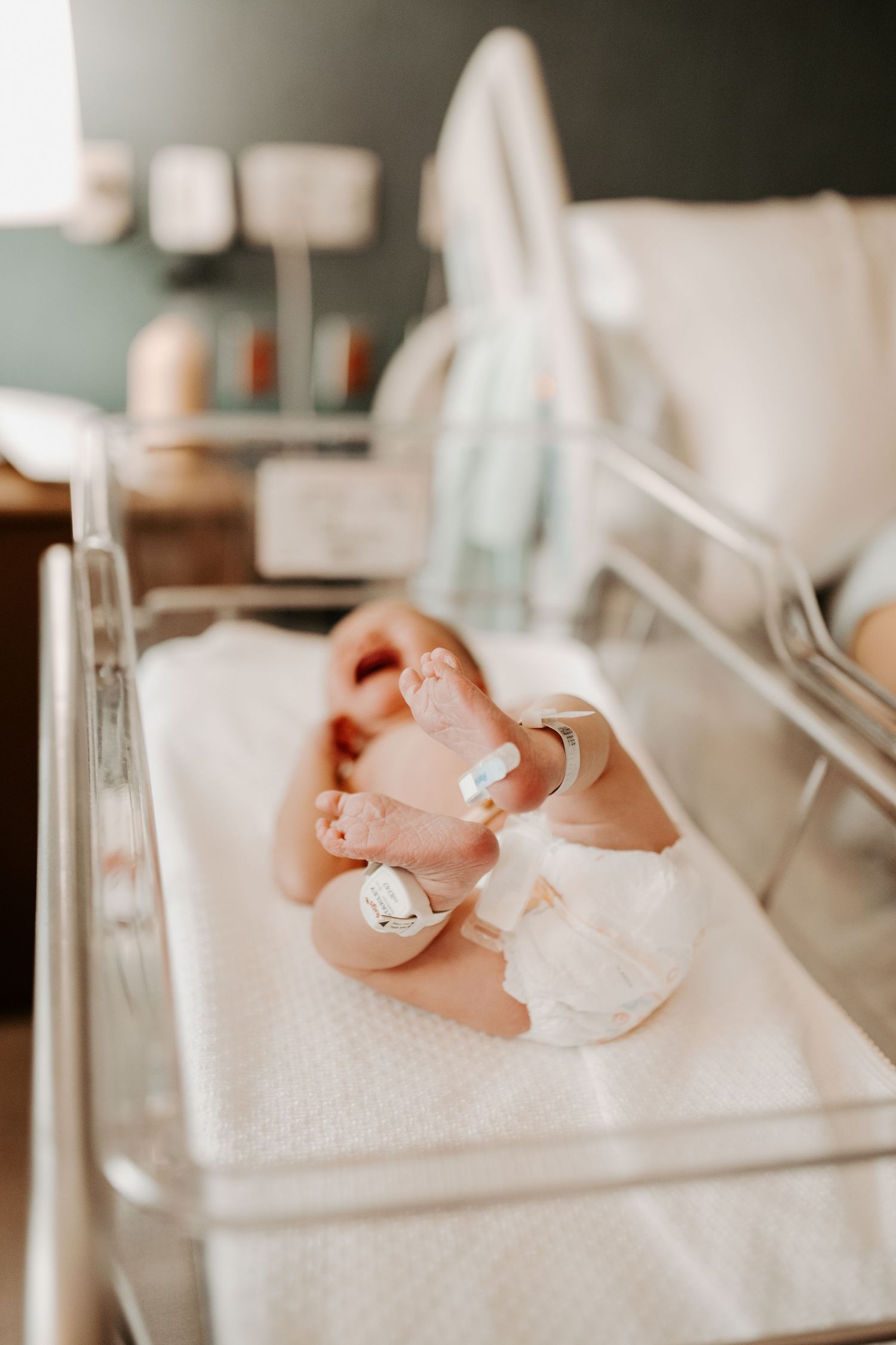 Photo of a baby in her hospital bassinet. Light and airy photo focused on the baby's toes.