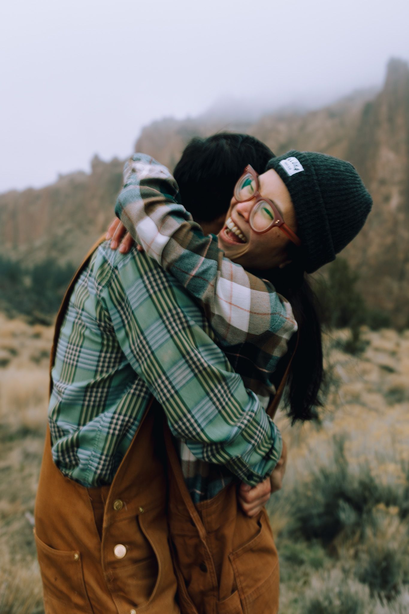Girl laughs while hugging her fiancé for portraits near Smith Rock state park