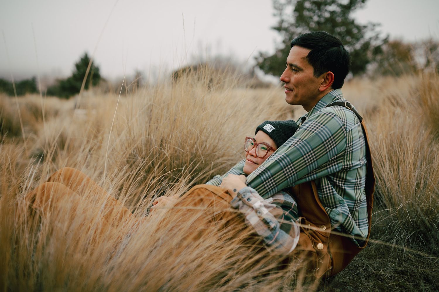 Couple sitting together in brush for a photoshoot