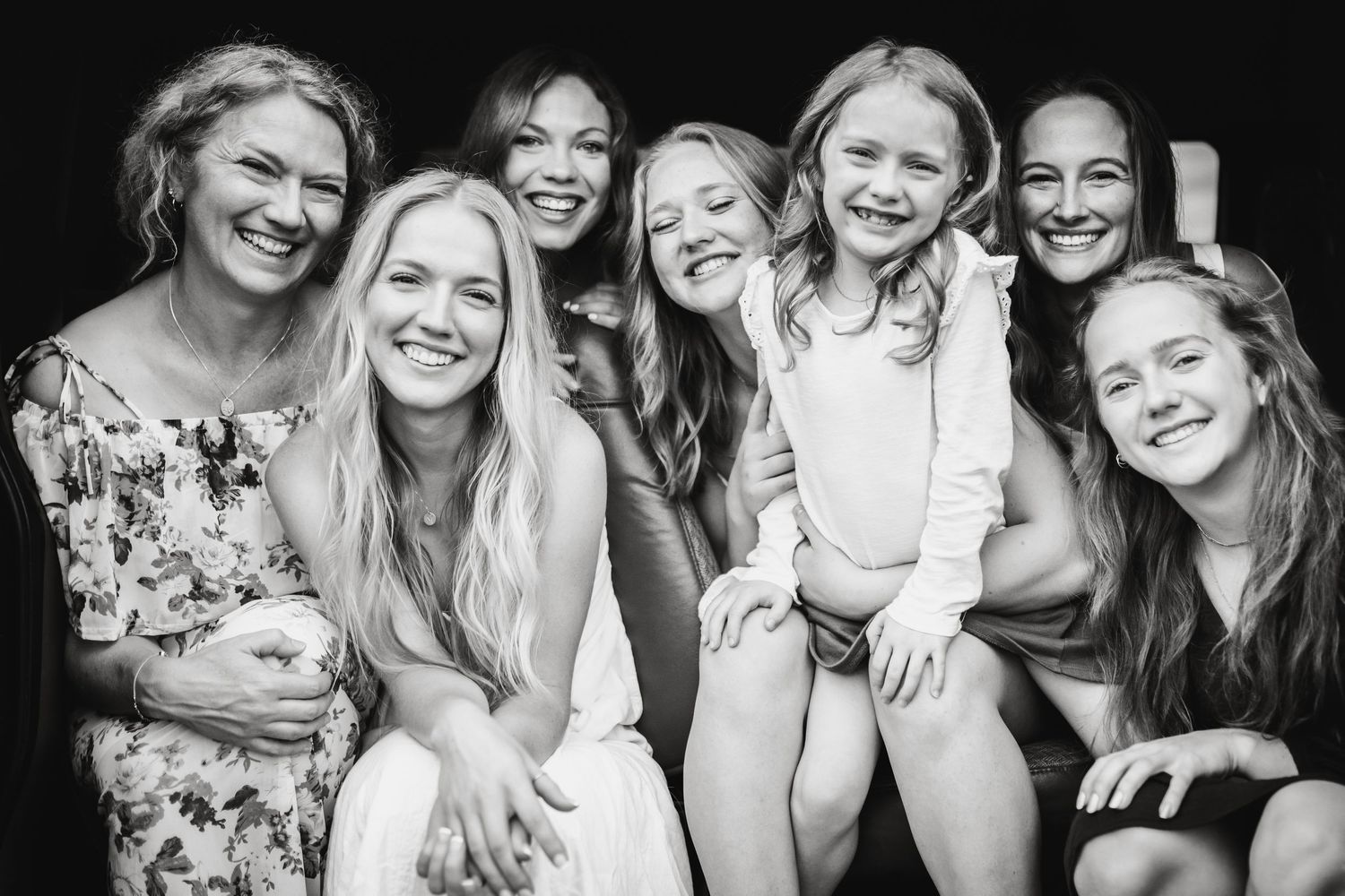 Mom and daughters huddled together for a portrait in black and white