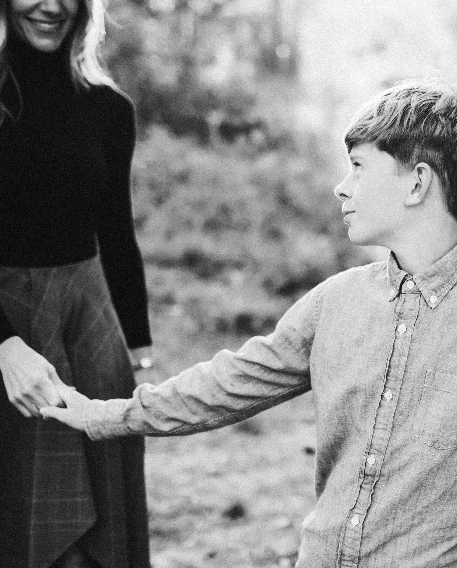 Candid black and white image of son holding his mothers hand