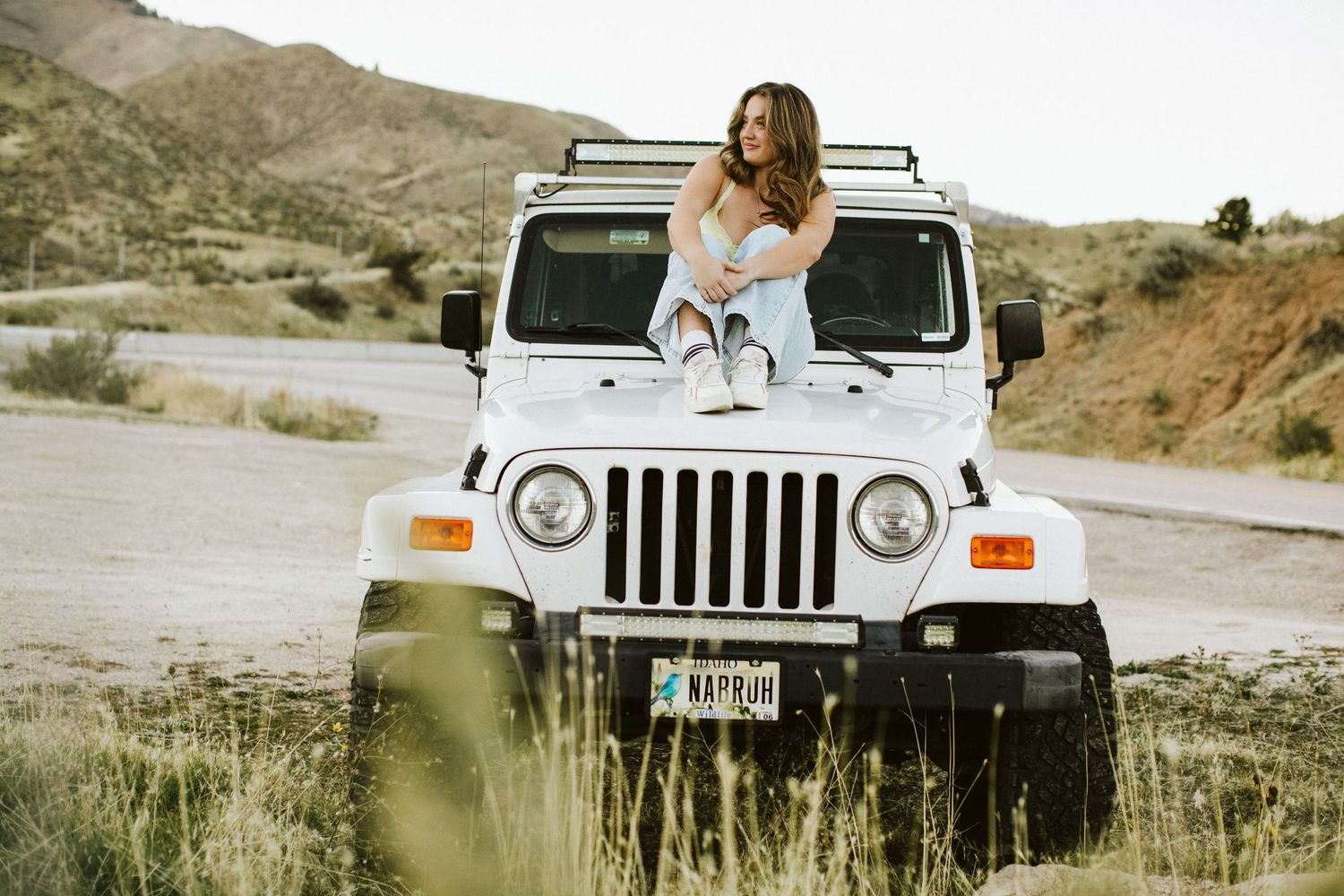 Young woman sitting on her car for senior portraits near Boise Idaho