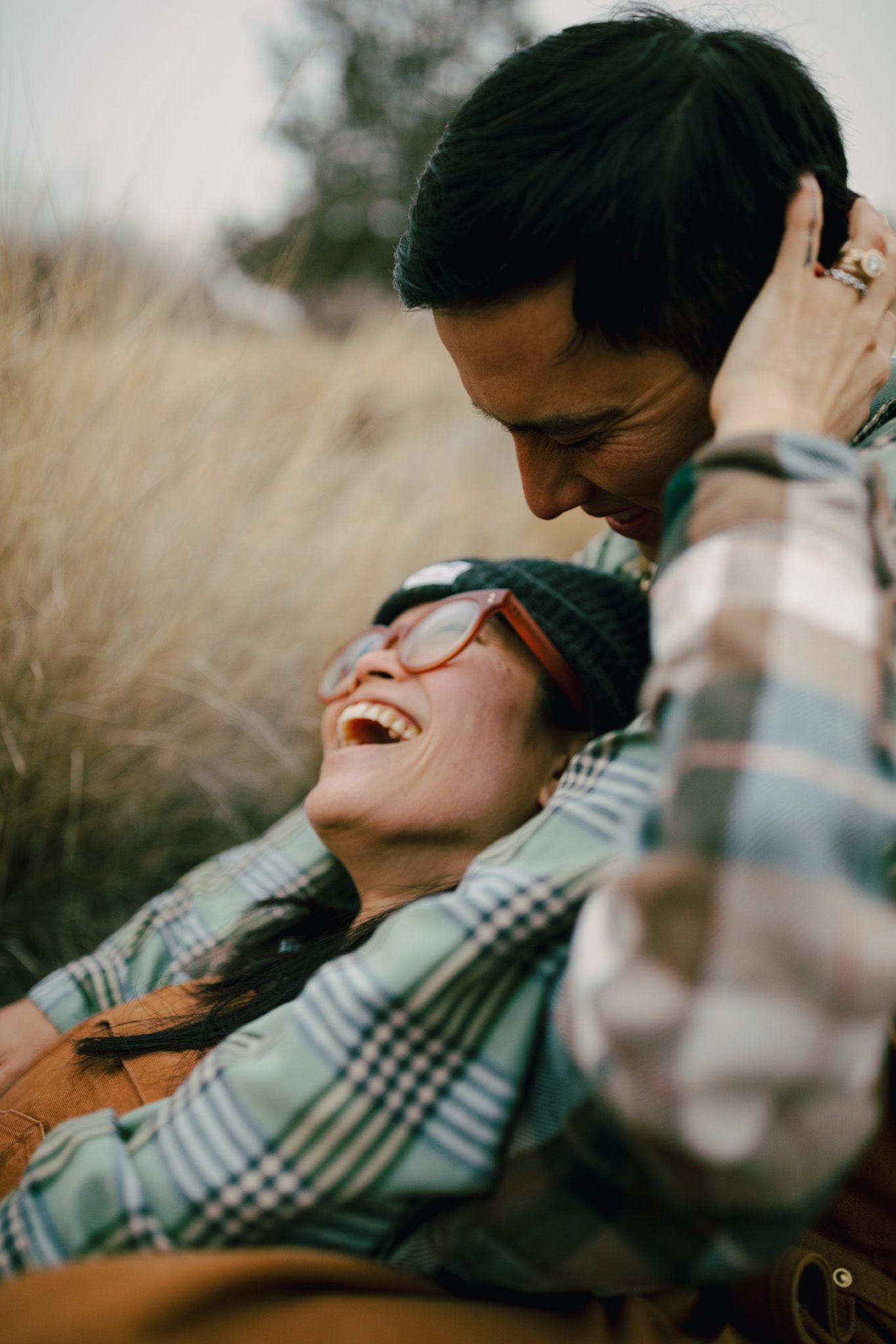 Wife laughing while sitting in her husbands lap for a photoshoot near Redmond Oregon