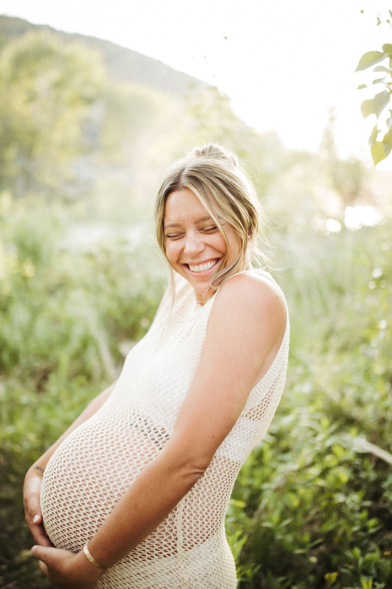Young woman holding her belly and laughing during a maternity photoshoot in Boise