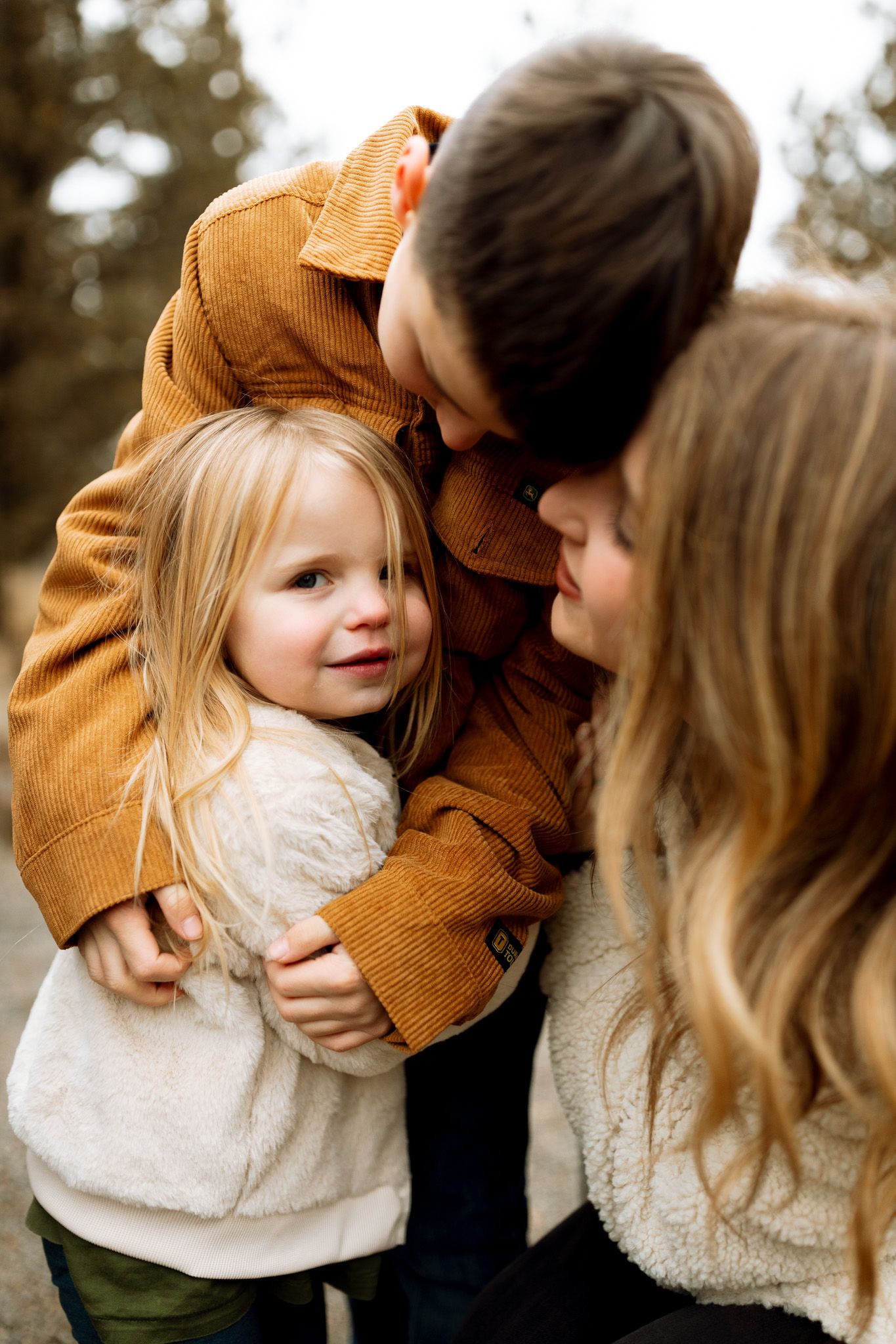 Mother smiling while her son hugs his sister during photoshoot