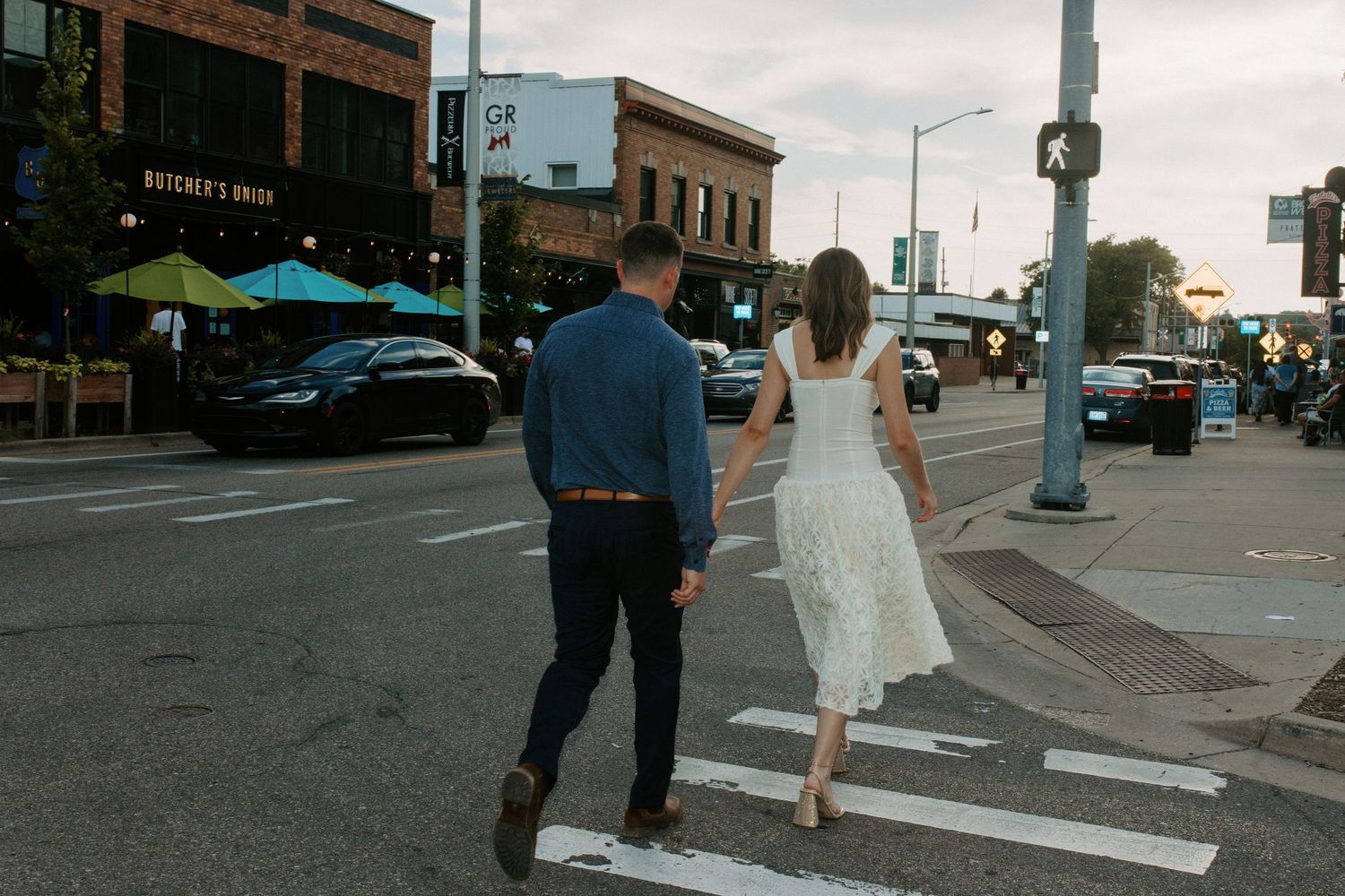 Couple walking down a city street with urban buildings in background.