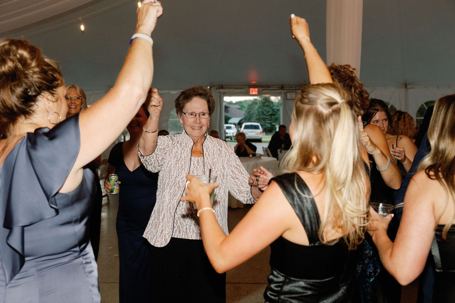 Wedding reception guests dancing and celebrating under indoor lighting.