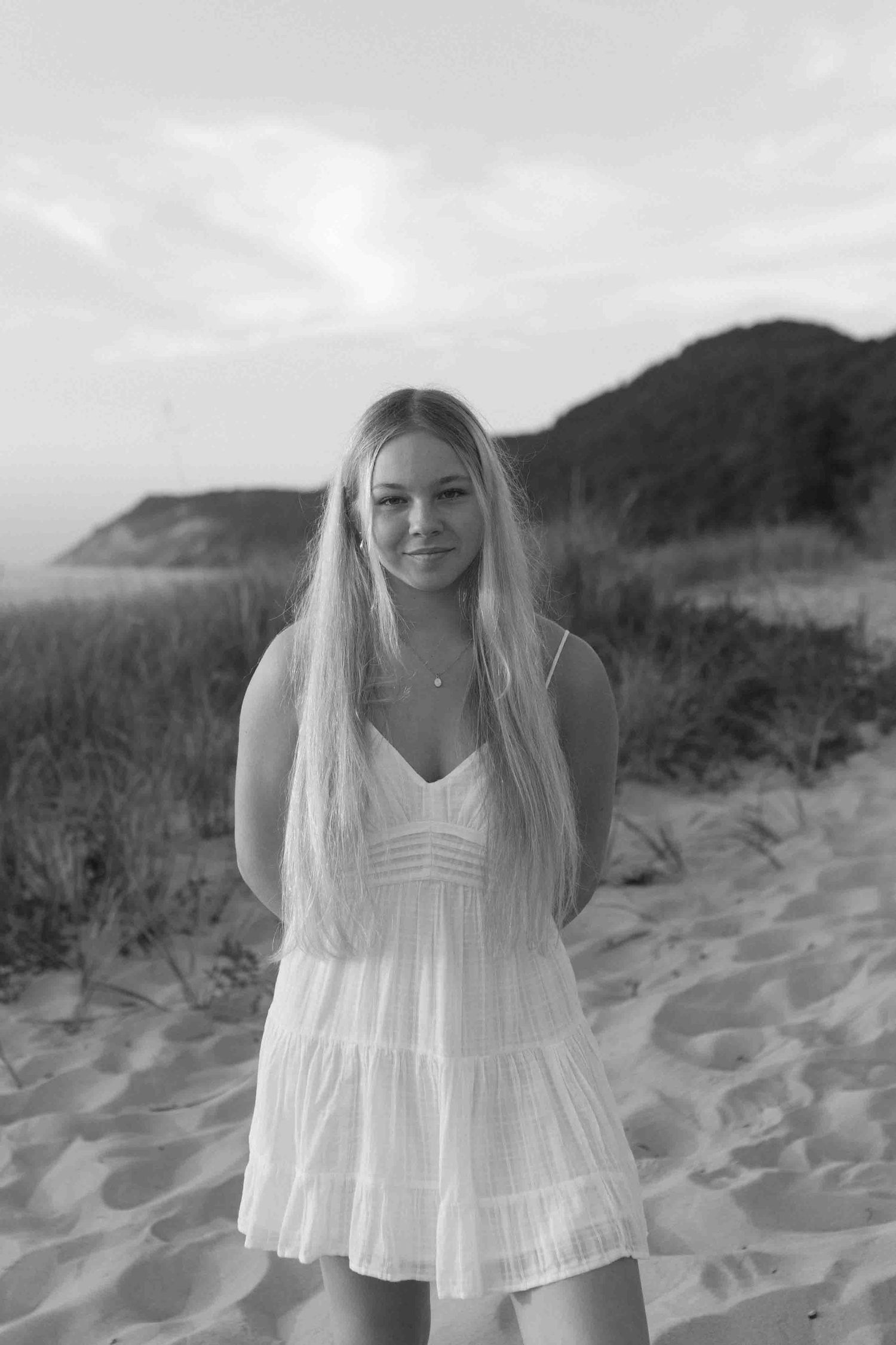 Black and white beach portrait with sand dunes and coastal mountains.