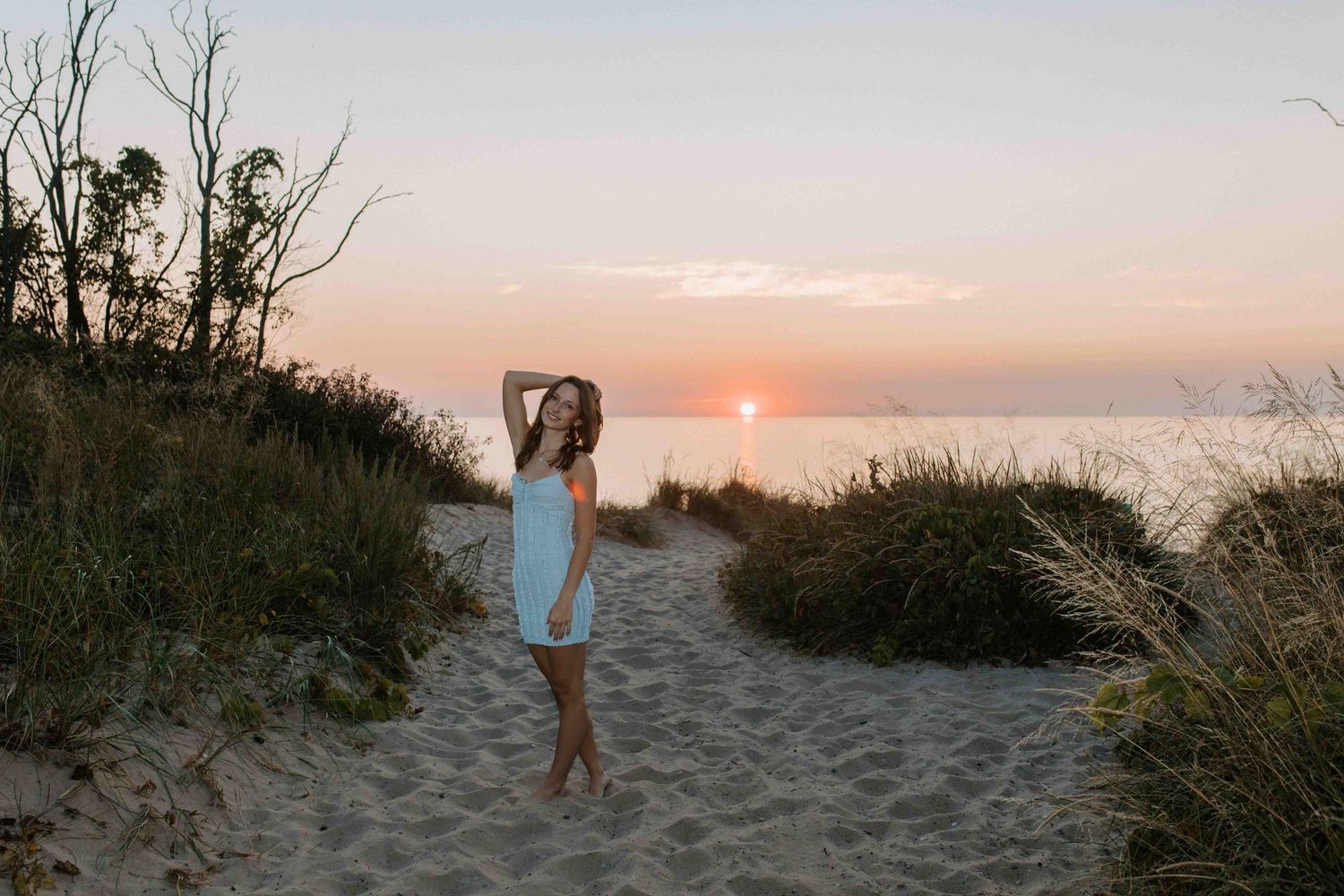 Peaceful beach scene at sunset with sandy pathways and coastal dunes.