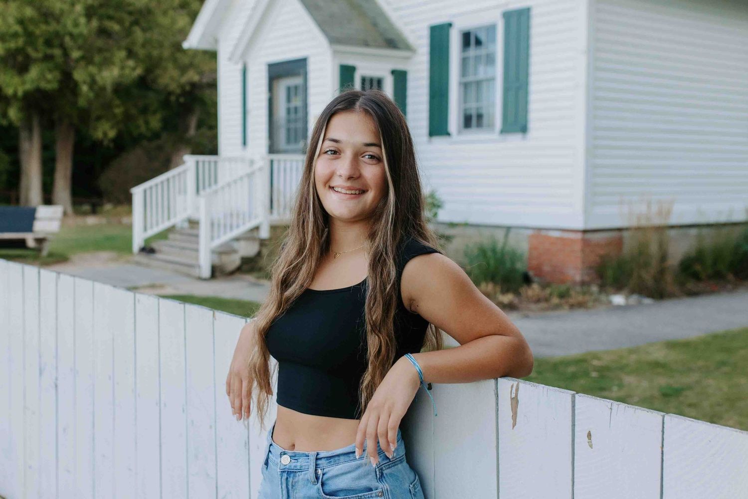Lifestyle portraits against a white farmhouse with green shutters and white picket fence.