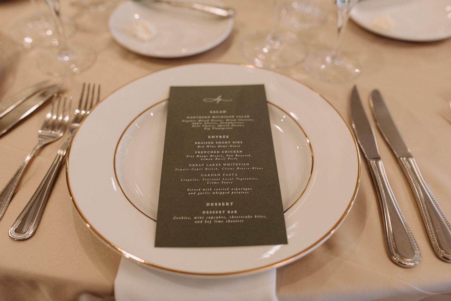 Formal place setting with menu card and gold-rimmed plates at wedding reception.