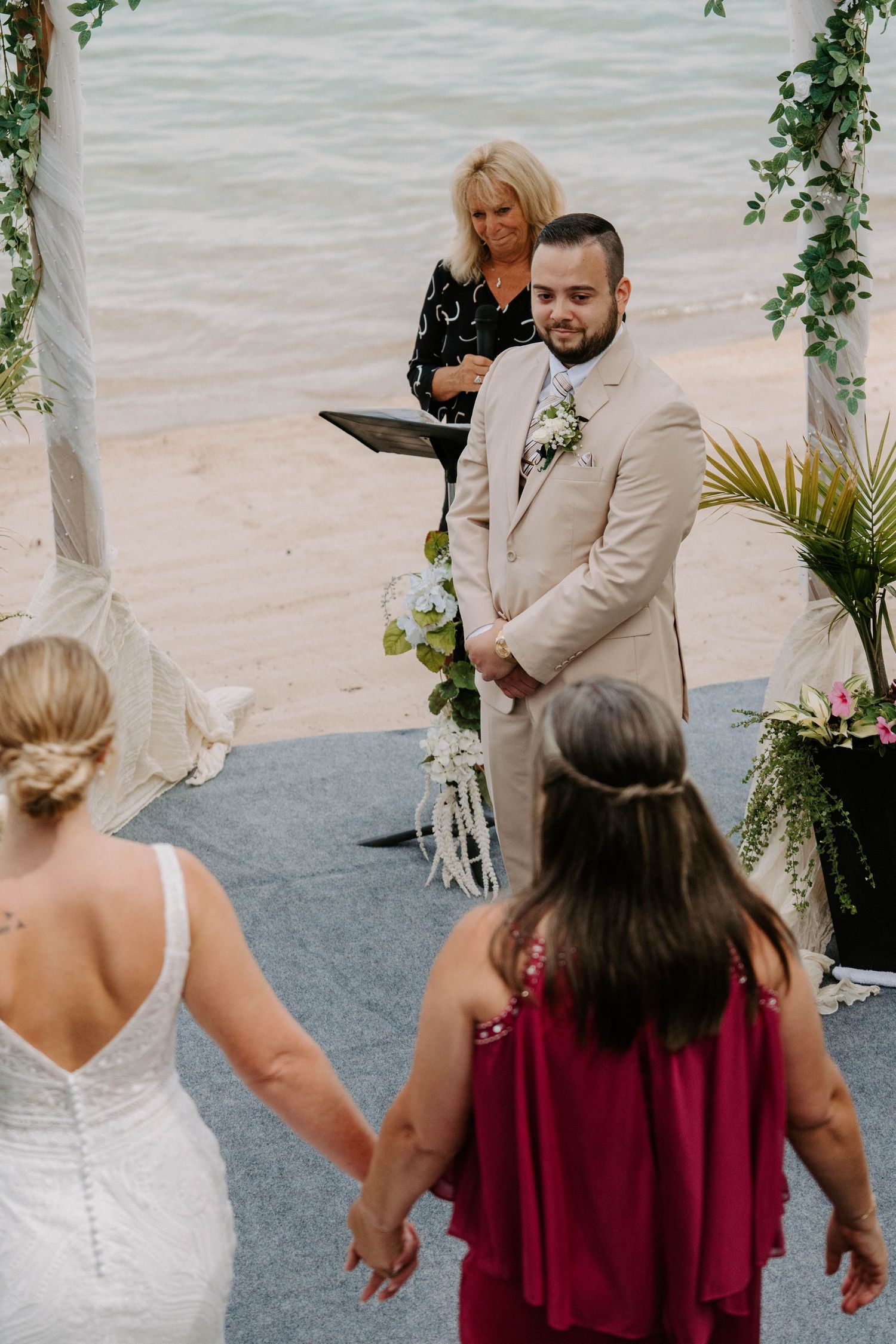 Wedding celebration on beach deck with floral arch and guests in attendance.