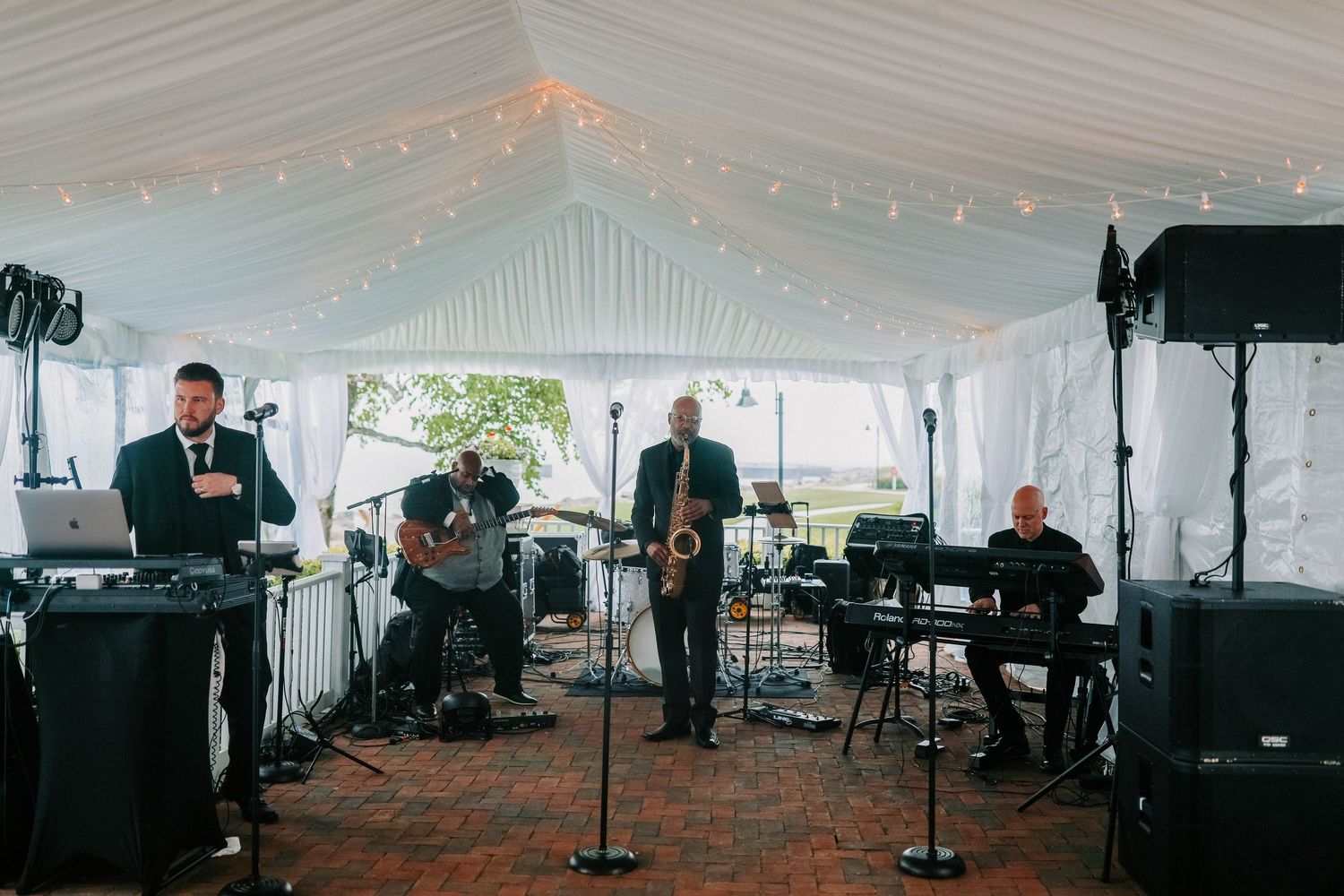 Large white tent set up for wedding reception with stage and lighting equipment.