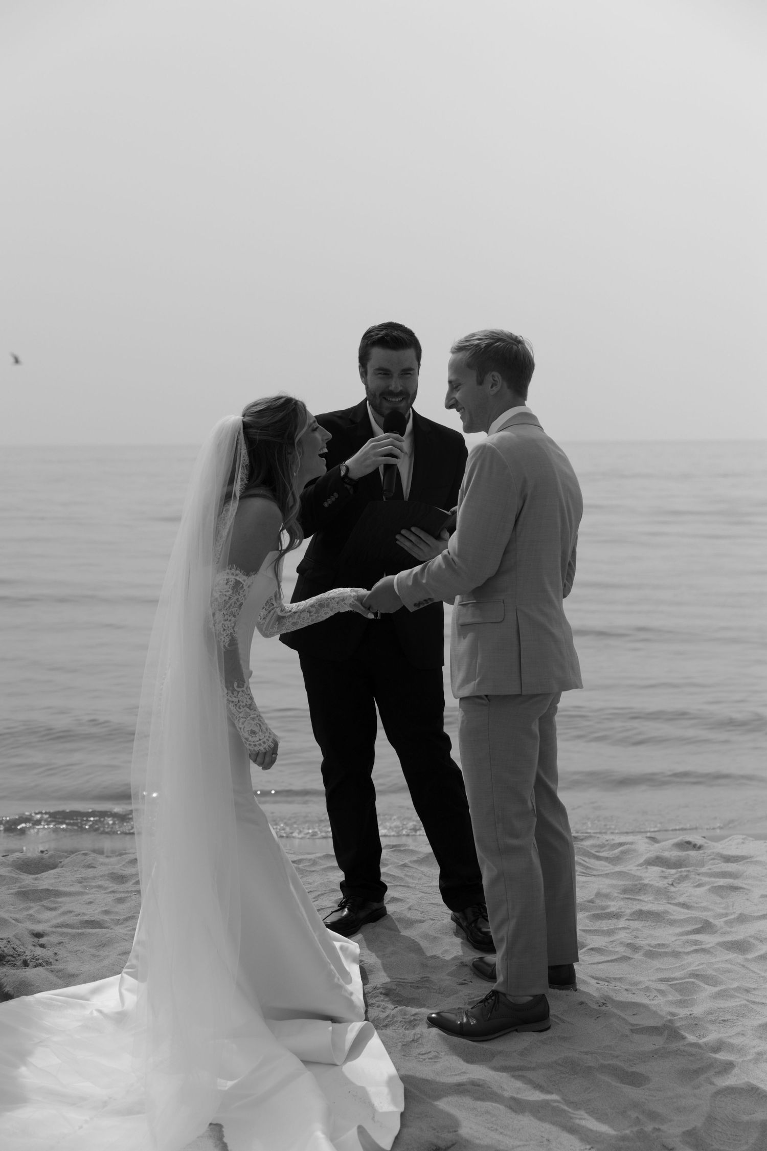 Black and white photo of a beach wedding ceremony with waves in the background.