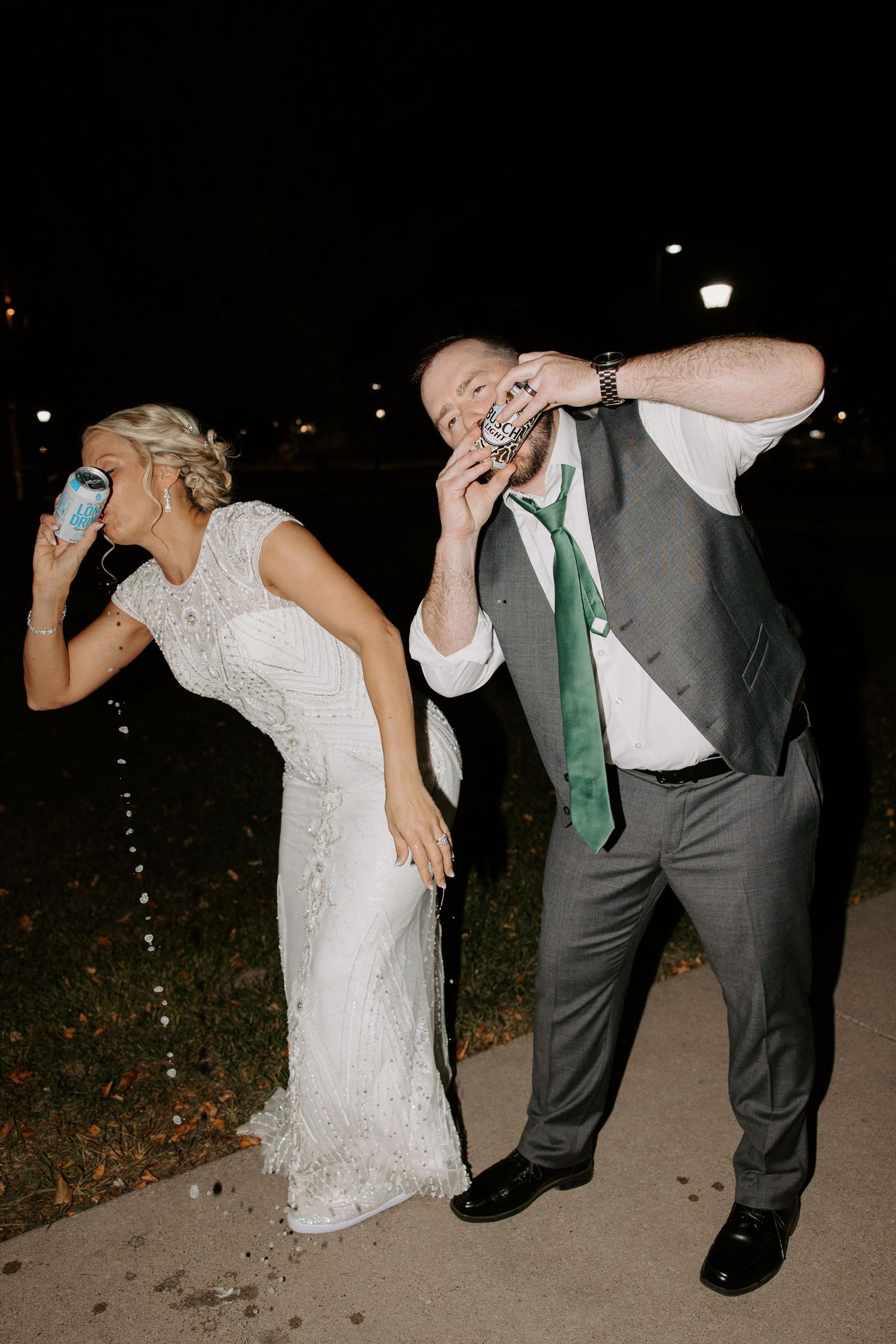 Wedding couple dancing and dipping playfully at night on an outdoor path.