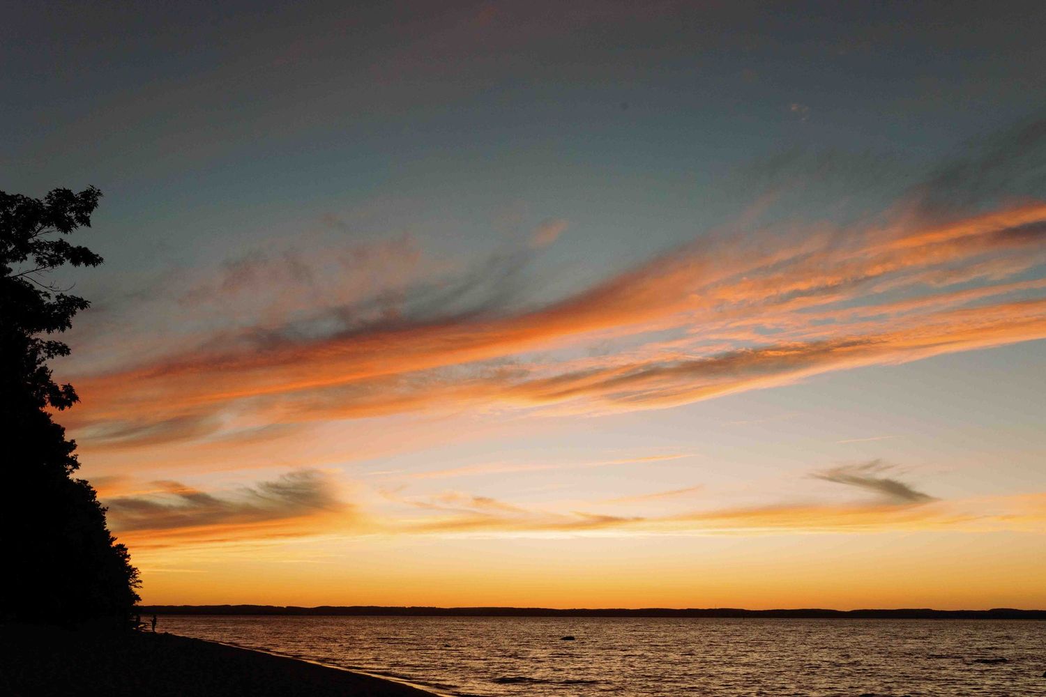 Dramatic orange and pink sunset sky over a calm ocean horizon.