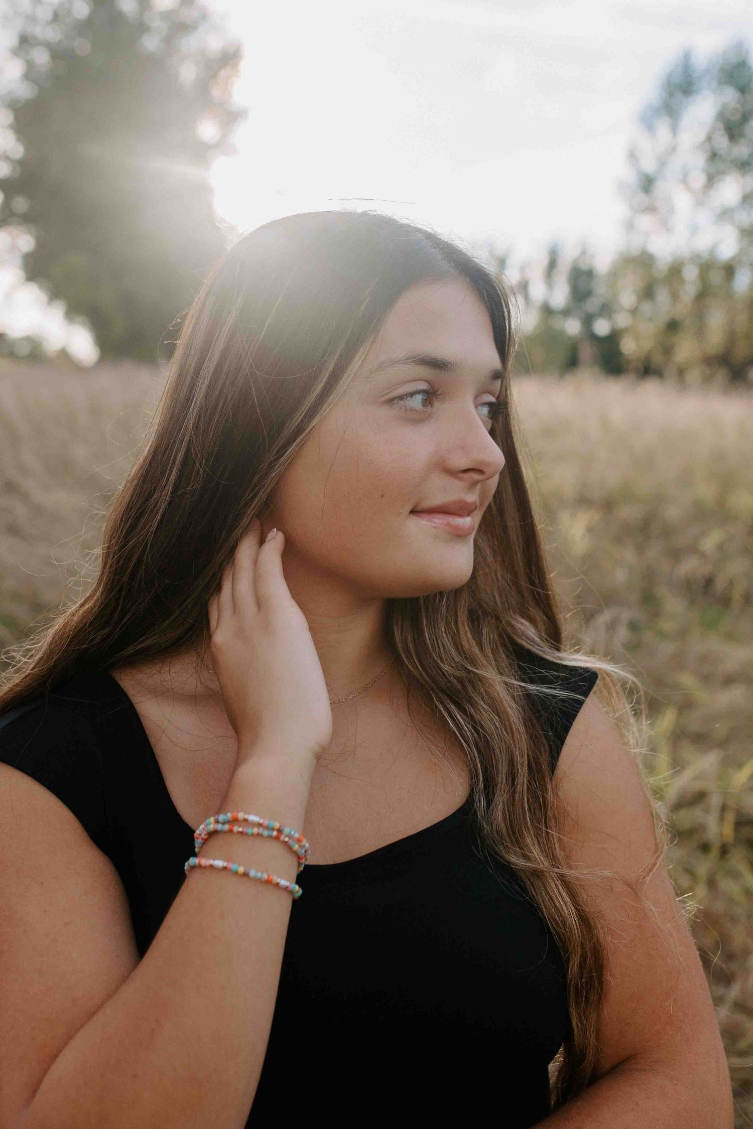 Natural sunlit portrait with beaded bracelets and black sleeveless top.