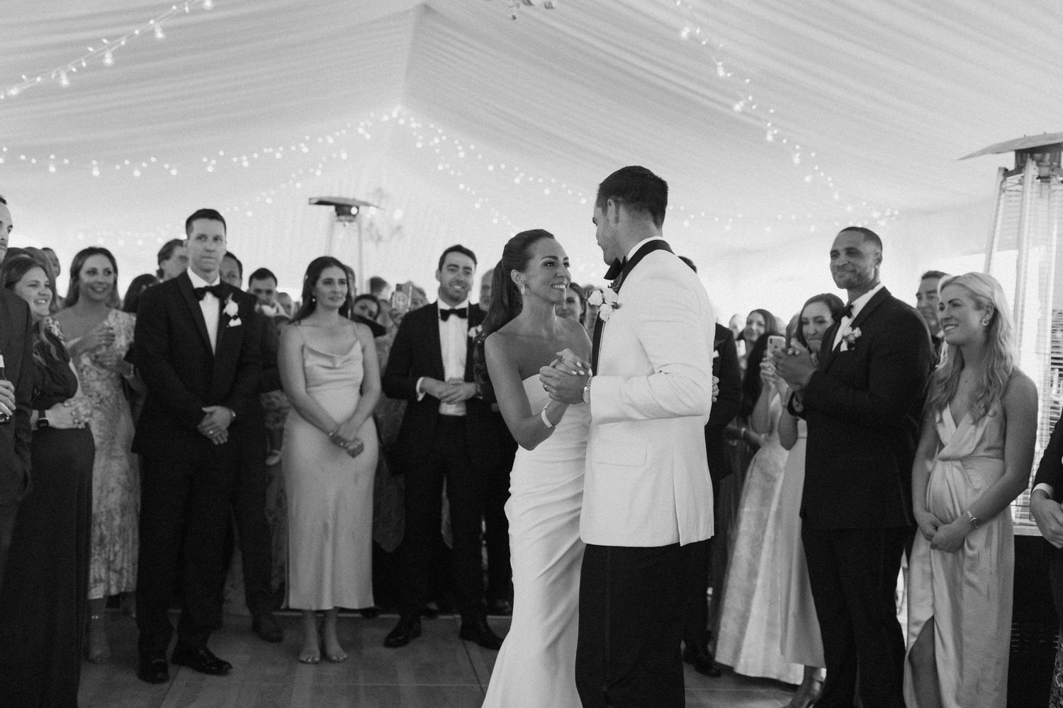 Wedding celebration in a tent venue with guests dancing and mingling on the dance floor.