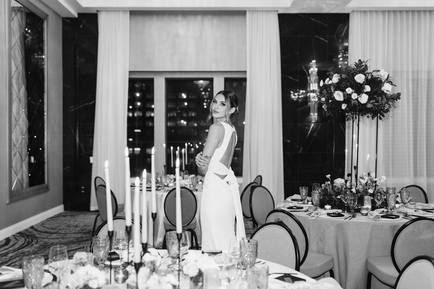 Elegant wedding reception setup with white tablecloths and floral centerpieces in a banquet hall.