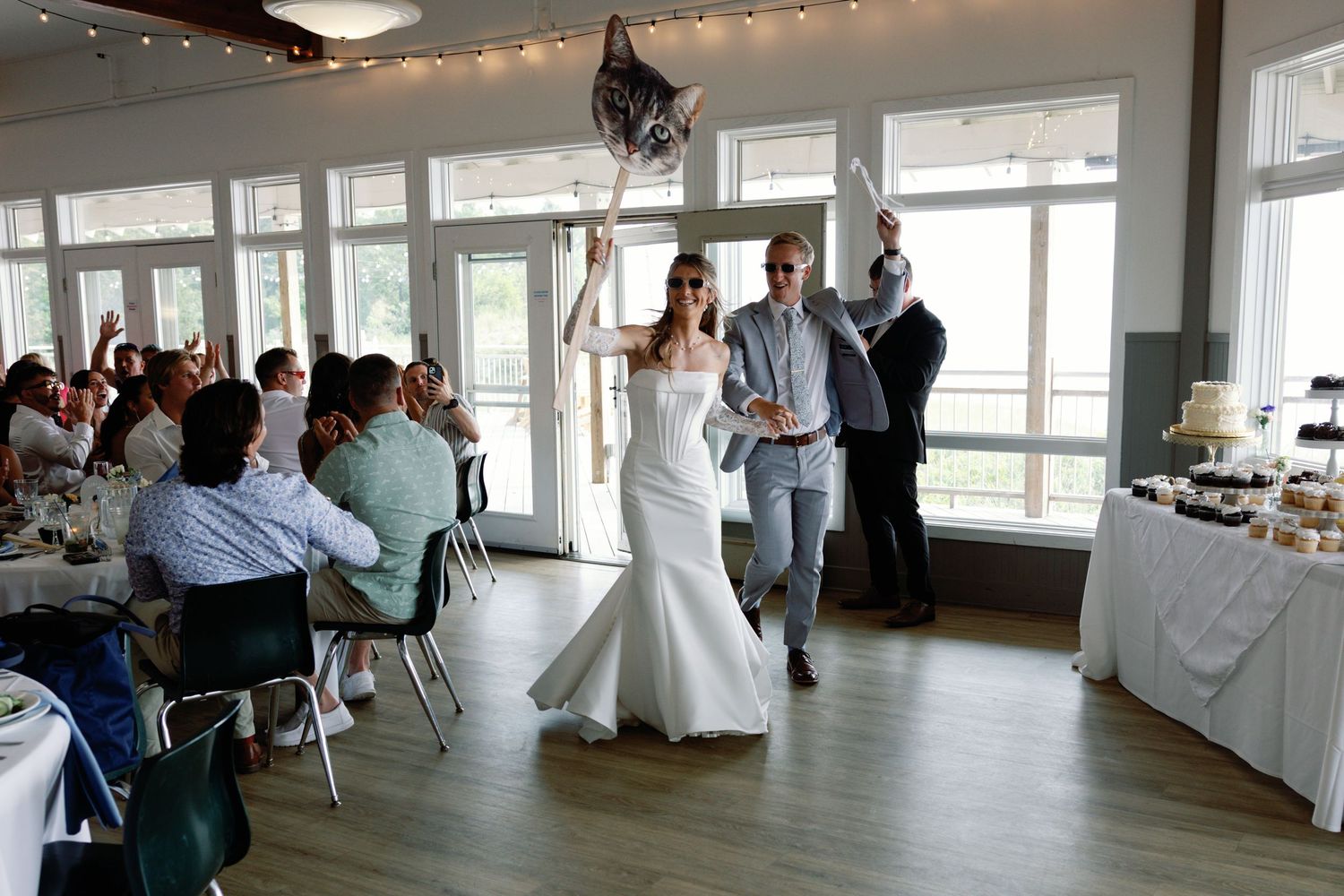 Large reception room with string lights and wedding guests enjoying the celebration.