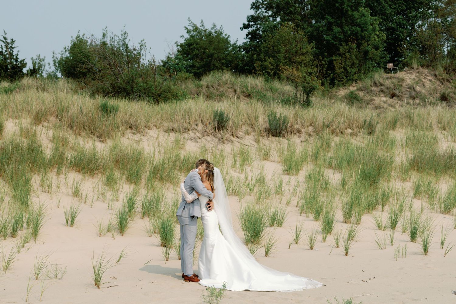 Beach wedding photography session among natural dunes with scattered grass.