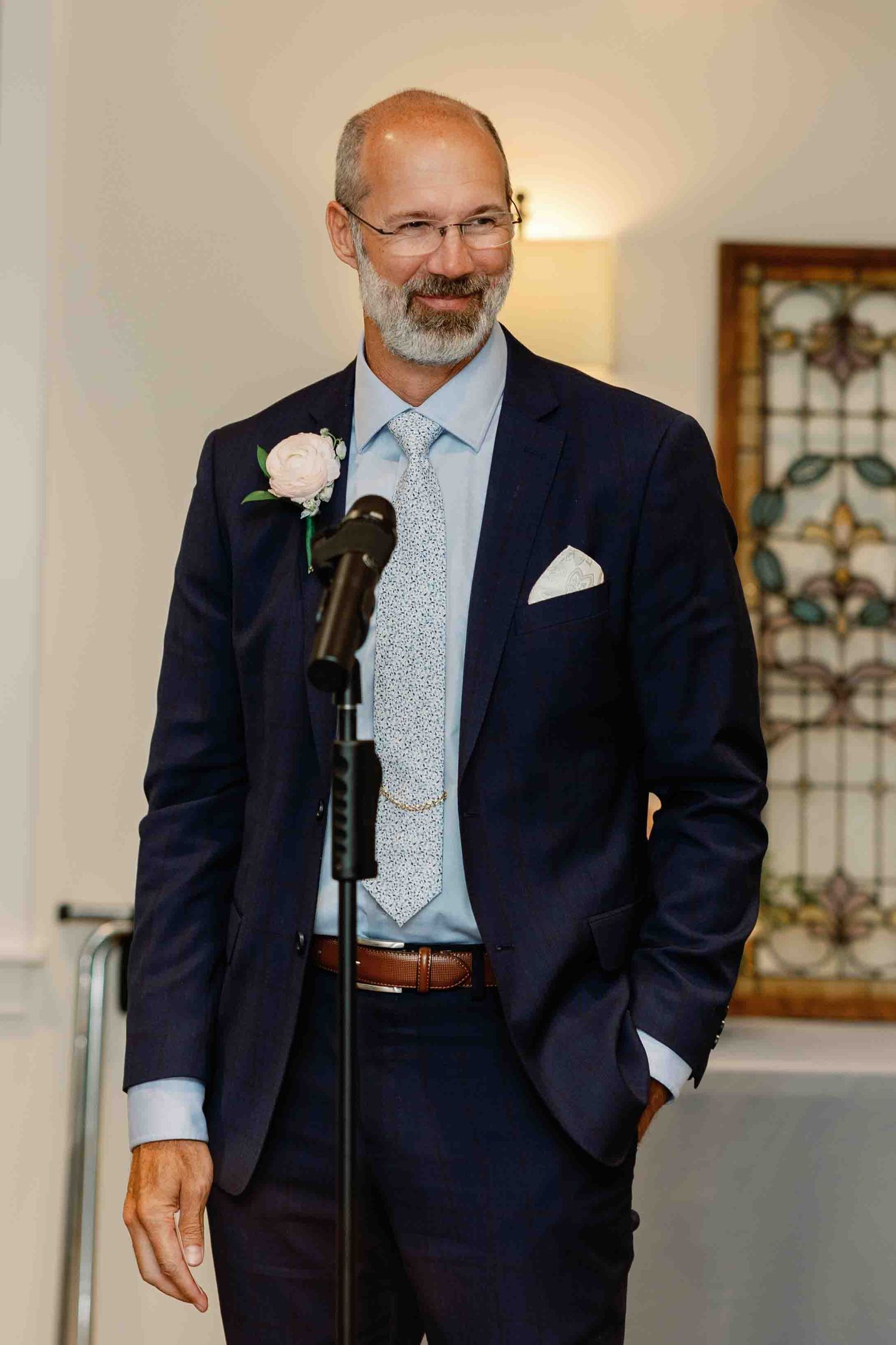 Speaker in a navy suit delivering remarks at a formal event podium.