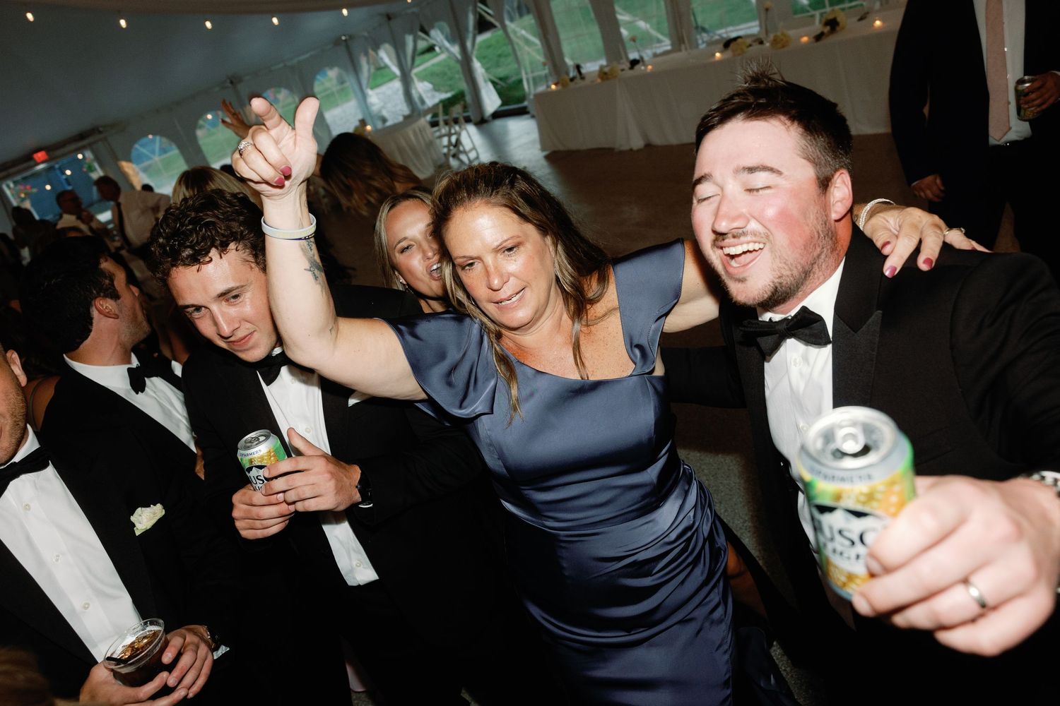 Guests enjoying drinks and dancing at a lively wedding reception celebration.