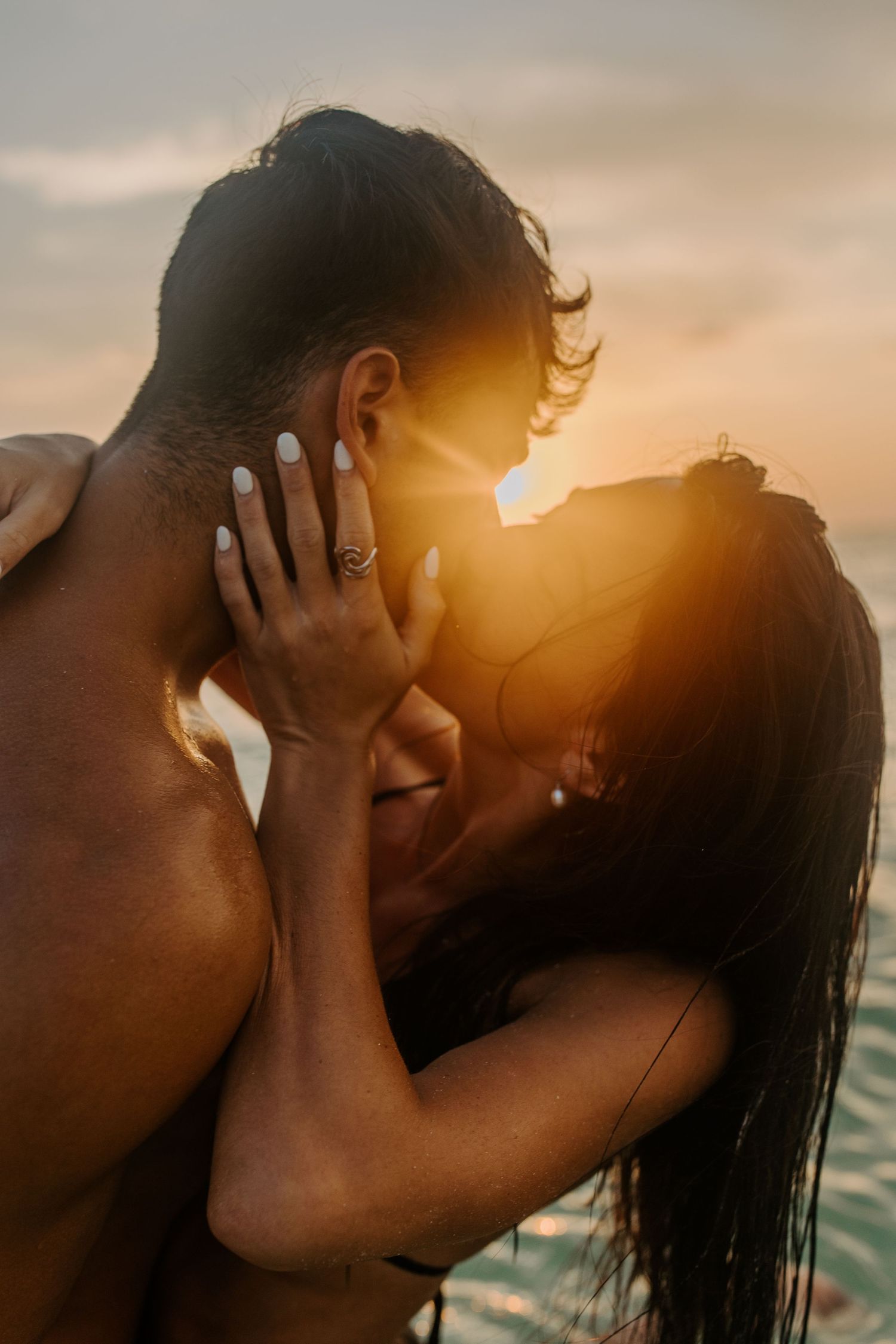 A silhouetted couple shares an intimate moment against a golden sunset backdrop.