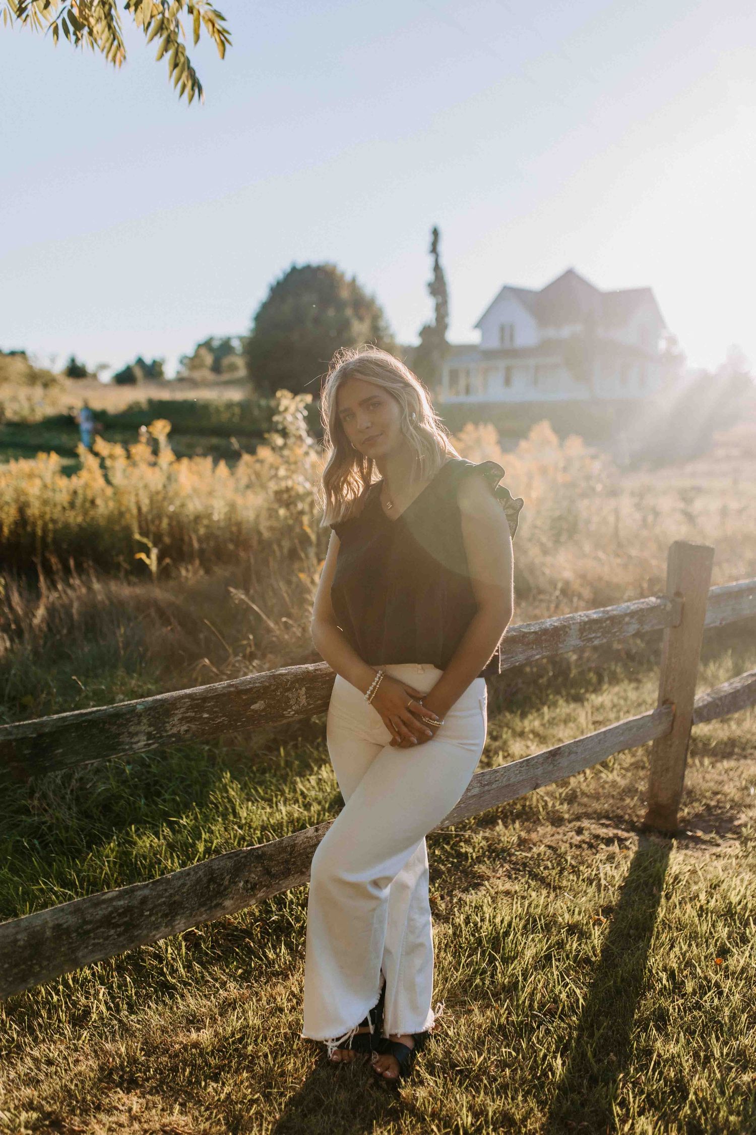 Sunset portrait session by a rustic wooden fence with warm golden lighting.
