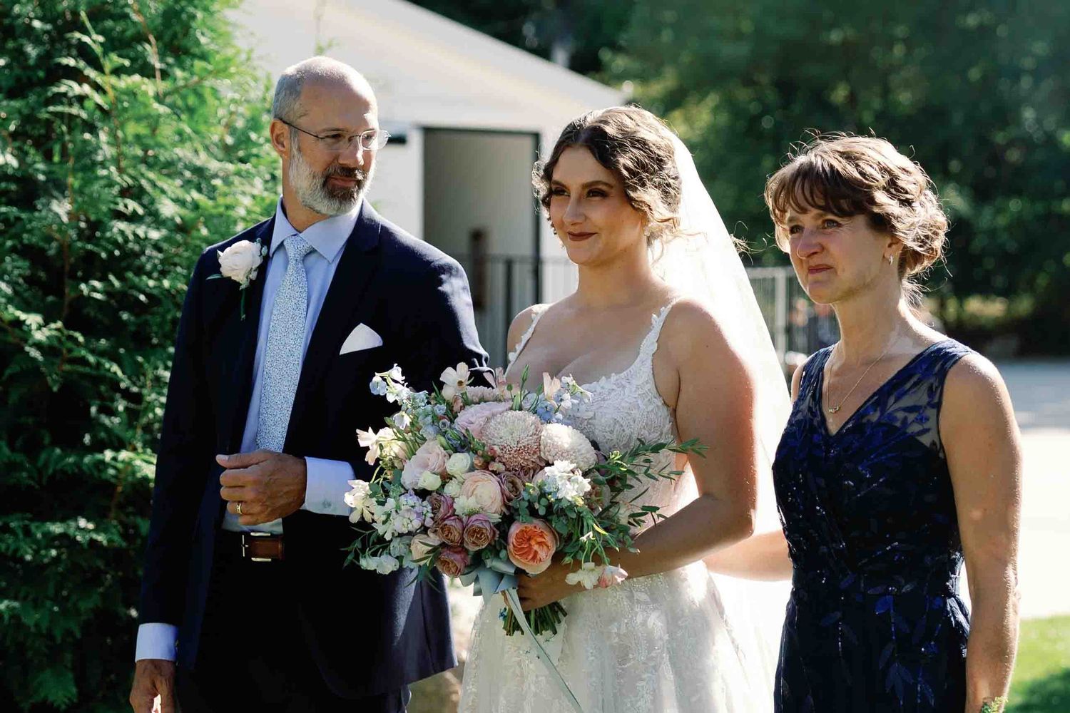 Wedding guests gather outdoors for a celebration on a sunny day.