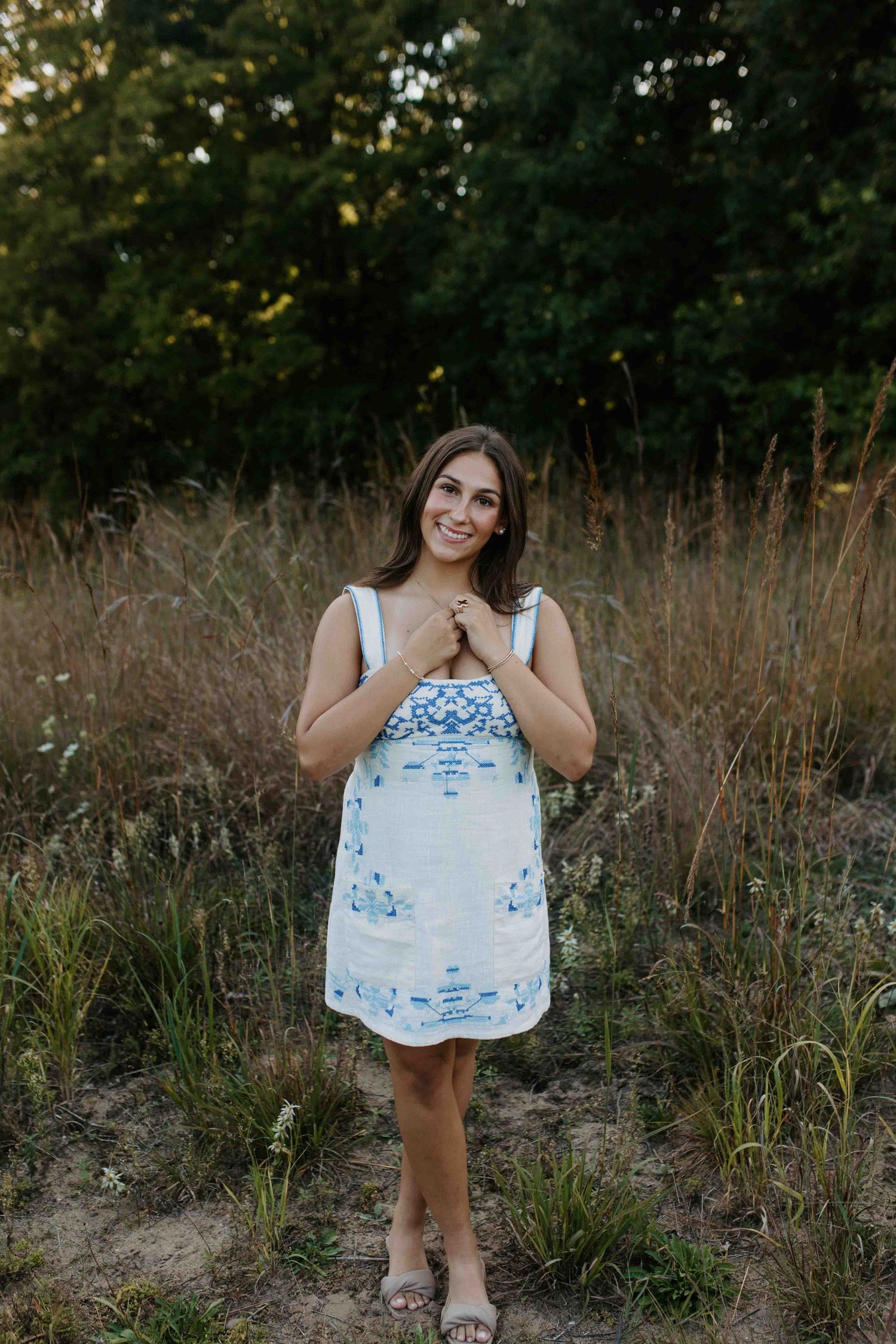 Artistic outdoor portrait in a white and blue dress surrounded by wild grasses.