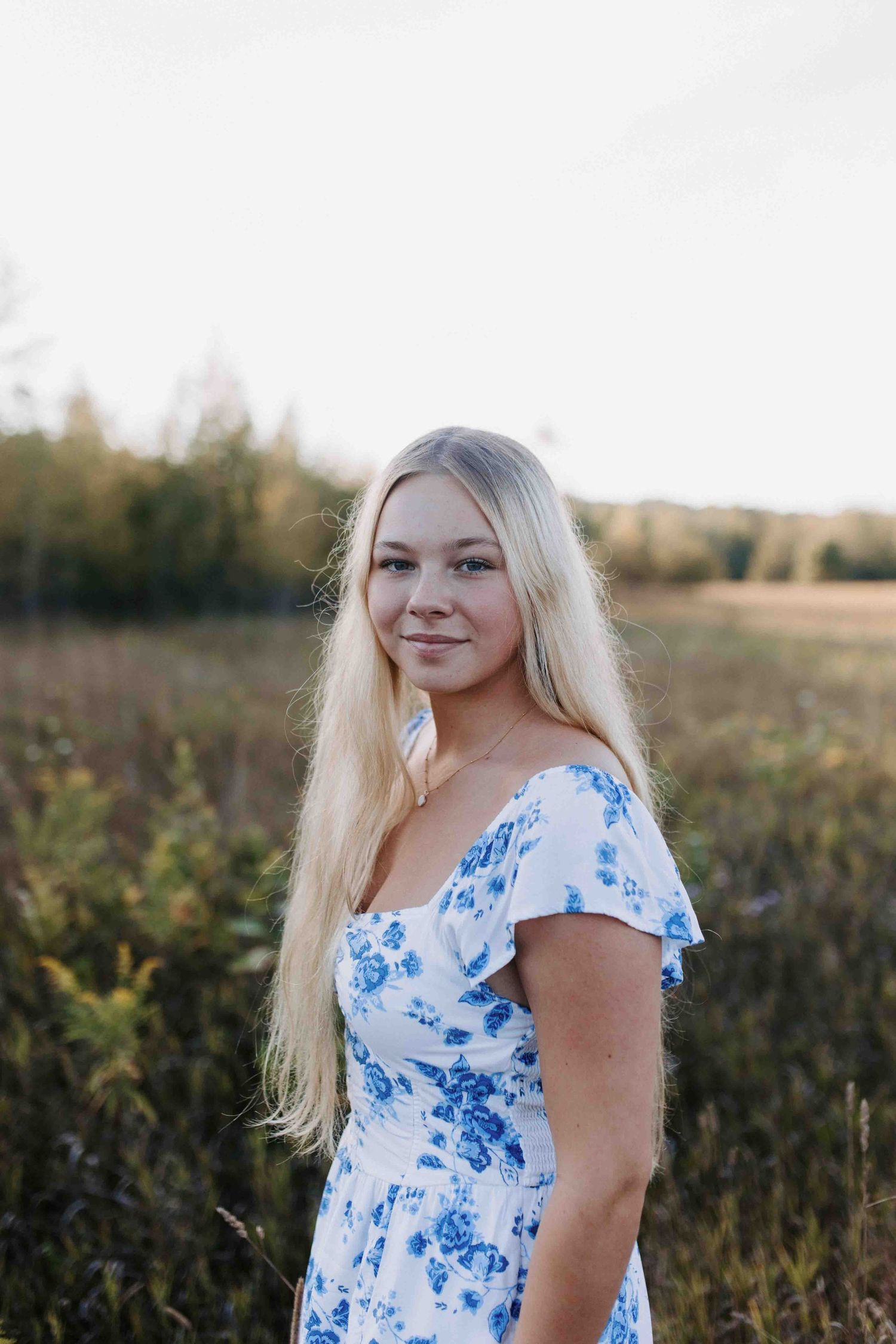 Portrait in blue and white floral dress against natural wildflower field.
