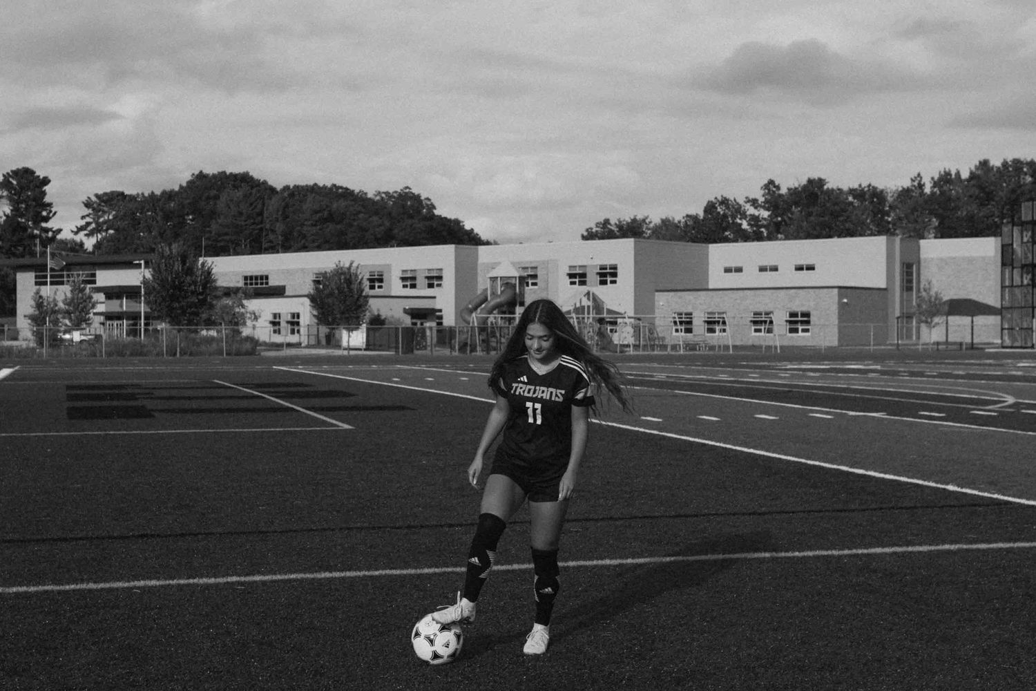 Soccer player practicing footwork drills in black uniform on sports field.