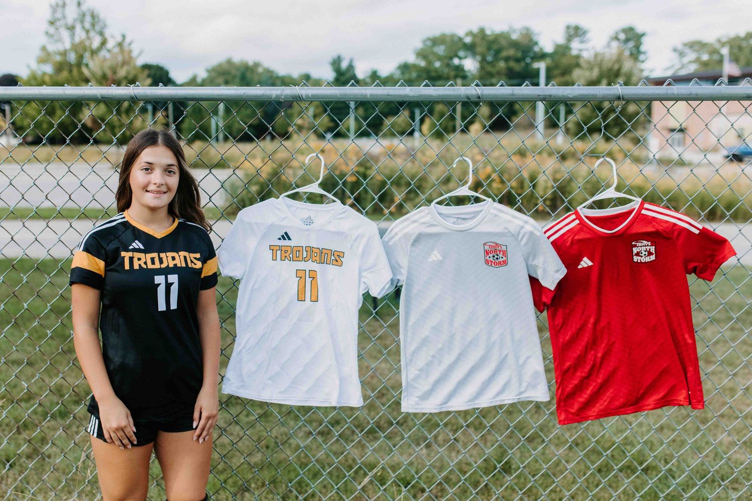 Soccer uniforms displayed on goal net with red and white jerseys visible.