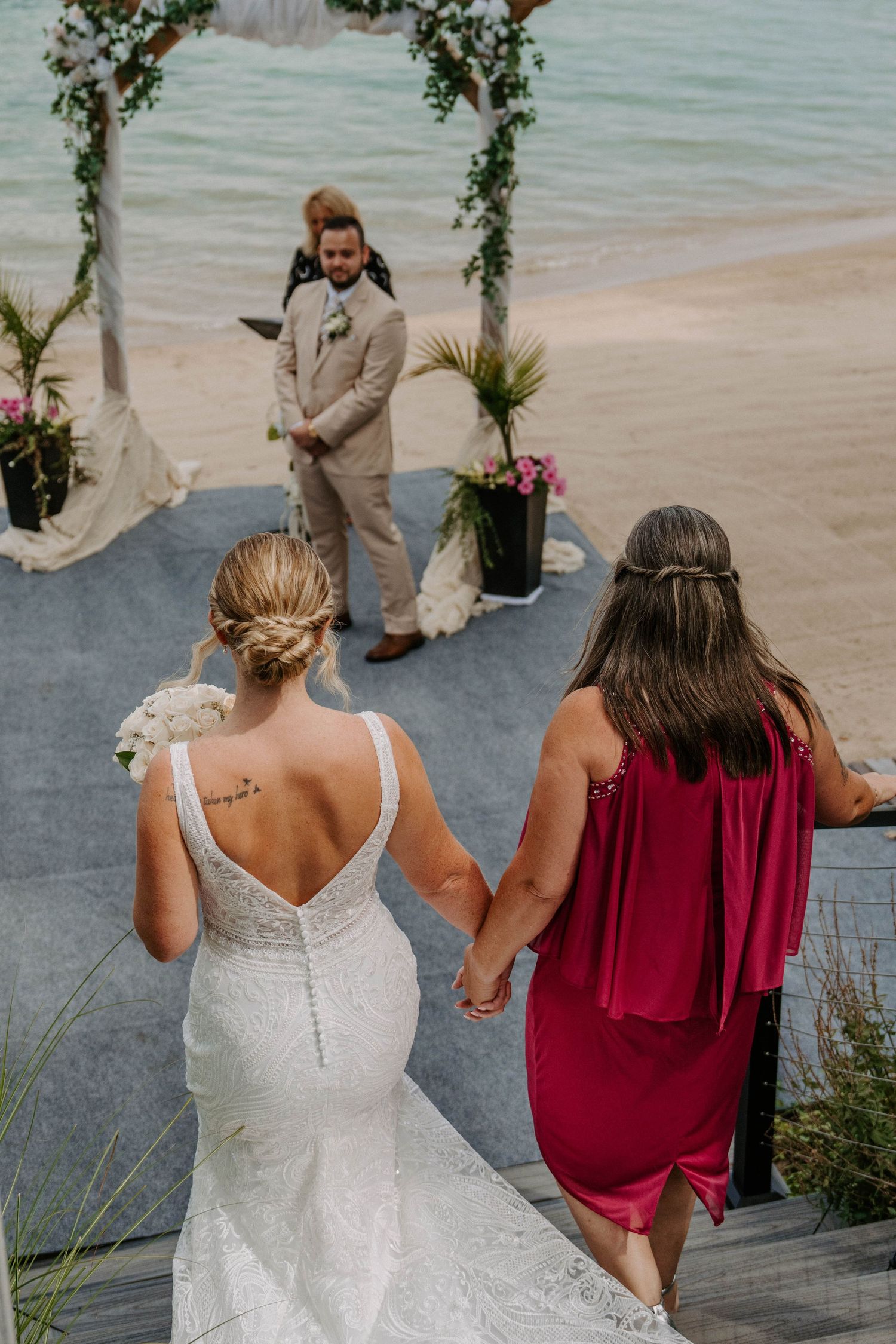 Wedding party members sharing joyful moments on beachfront deck.
