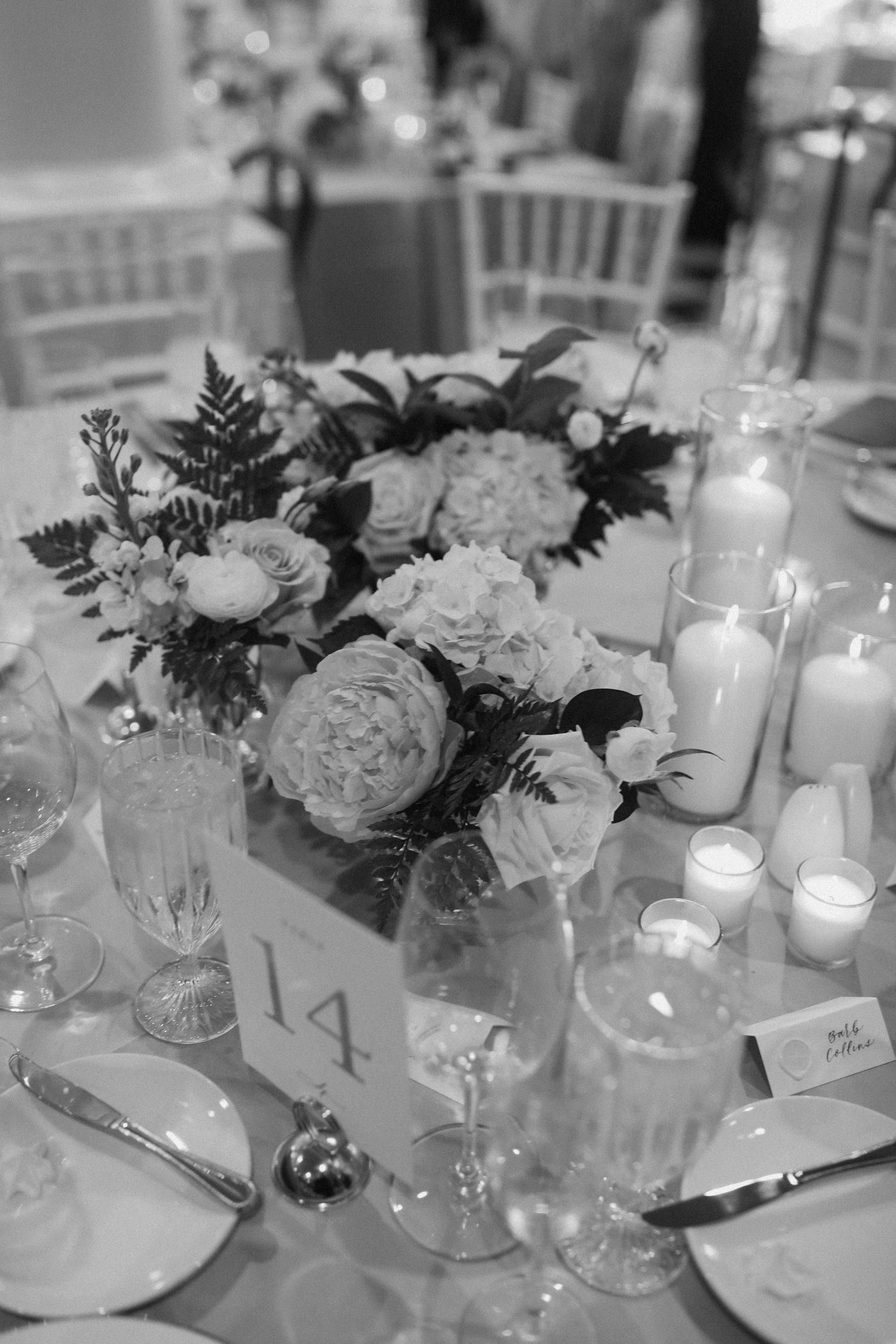 Black and white photo of wedding table centerpieces with roses and candlelight.