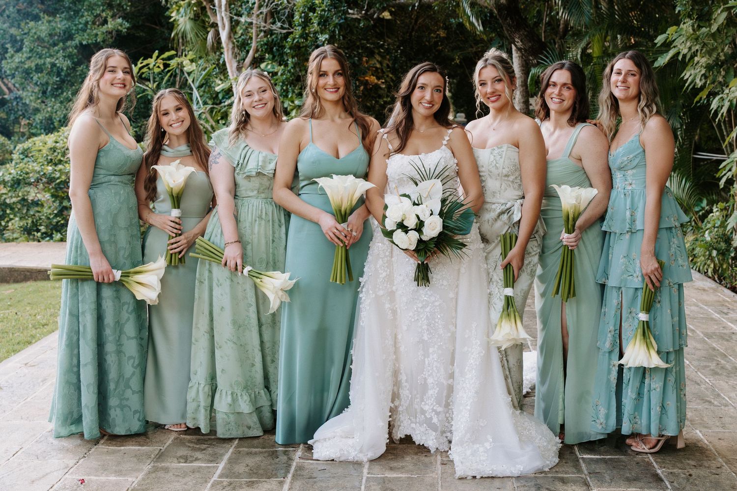Bridal party wearing sage green dresses standing together for formal photos.