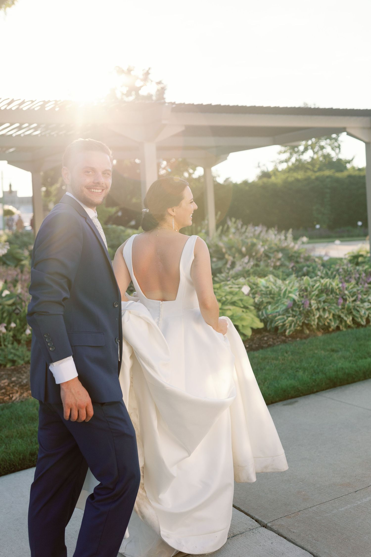 Couple sharing romantic moment at sunset in formal wedding attire.