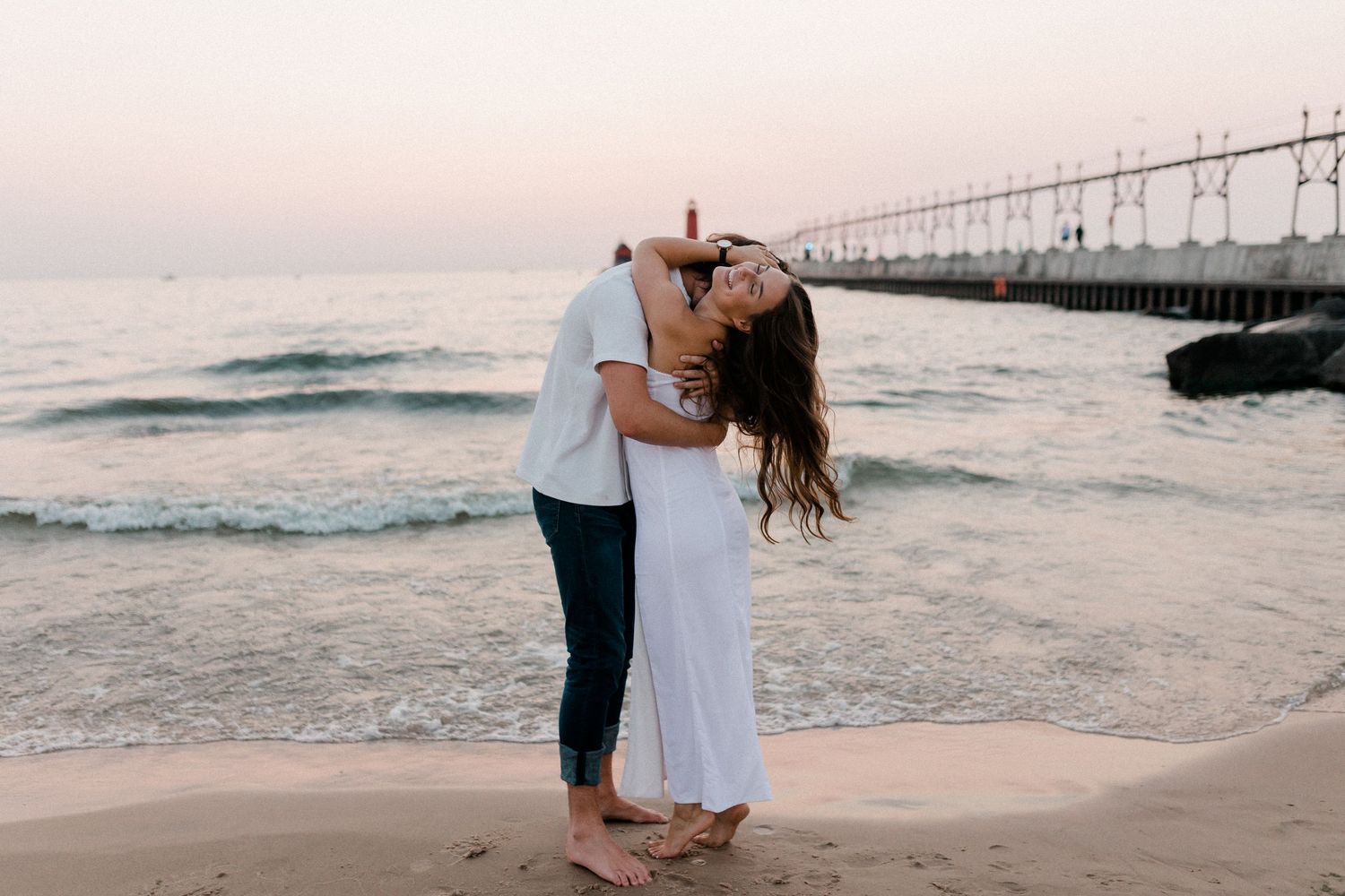 Romantic beach photoshoot with waves and pier in the background.