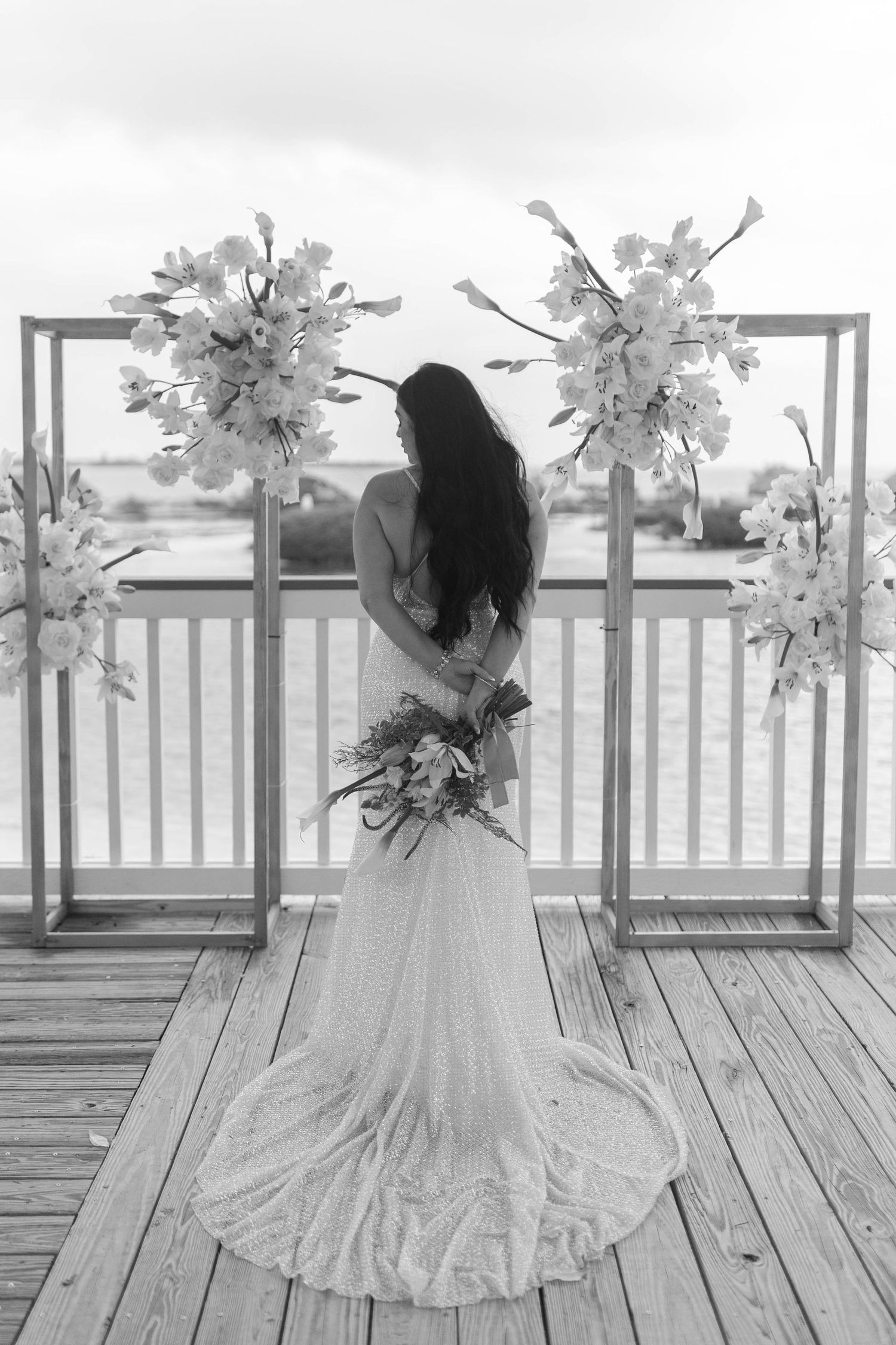 Black and white image of a flowing white dress against decorative light fixtures on a deck.