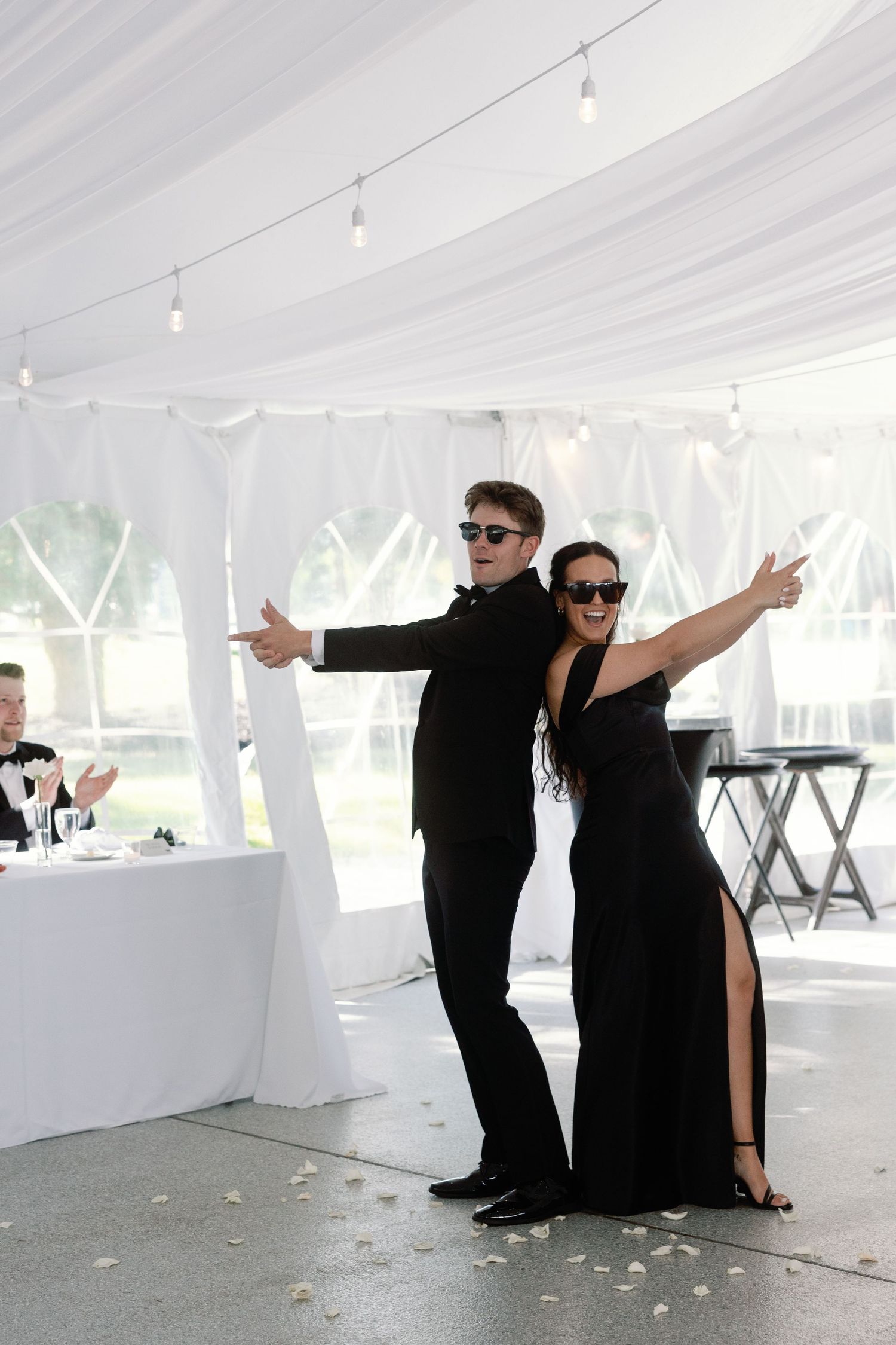 Event staff in black attire strike dramatic poses inside a white reception tent.