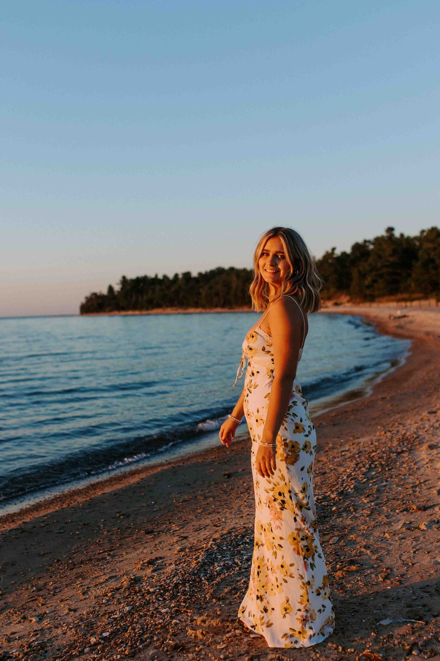 Full length portrait series showing woman in floral dress walking along beach at dusk.