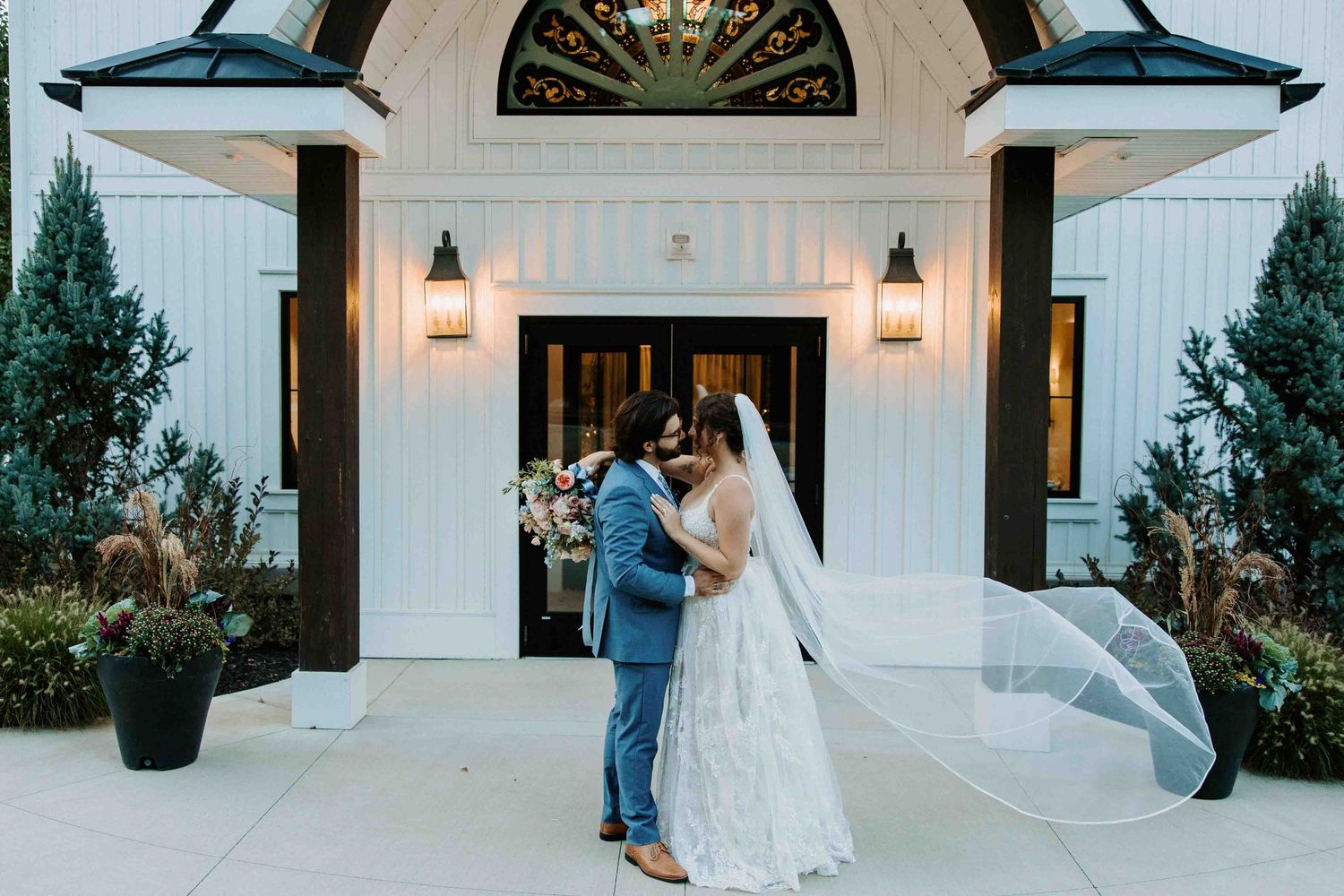 Wedding couple sharing romantic moments outside a white chapel with elegant architecture.