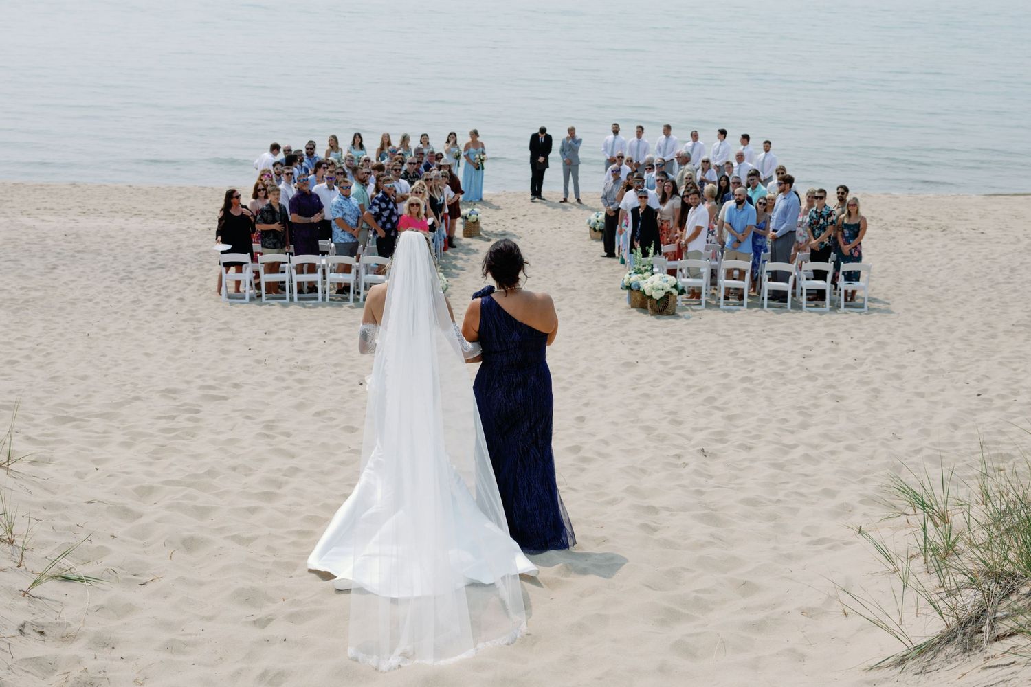 Guests gather for an intimate beach wedding ceremony with chairs arranged in rows.
