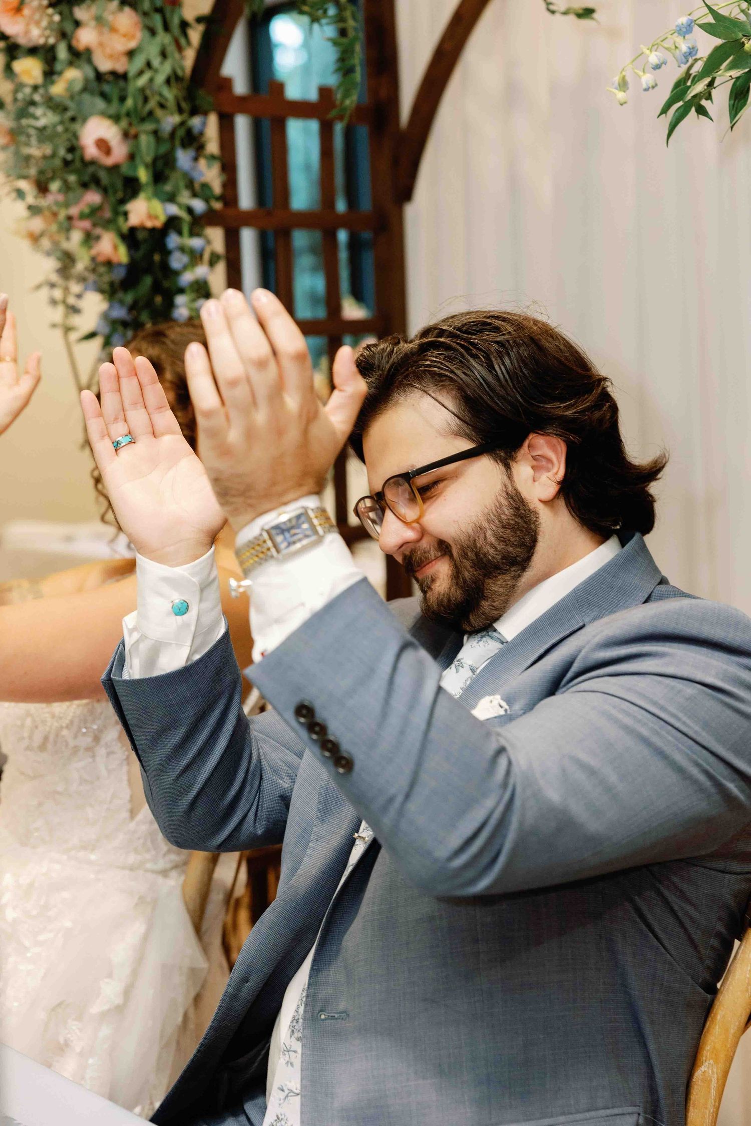Wedding guest in grey suit showing emotional reaction during reception celebration.